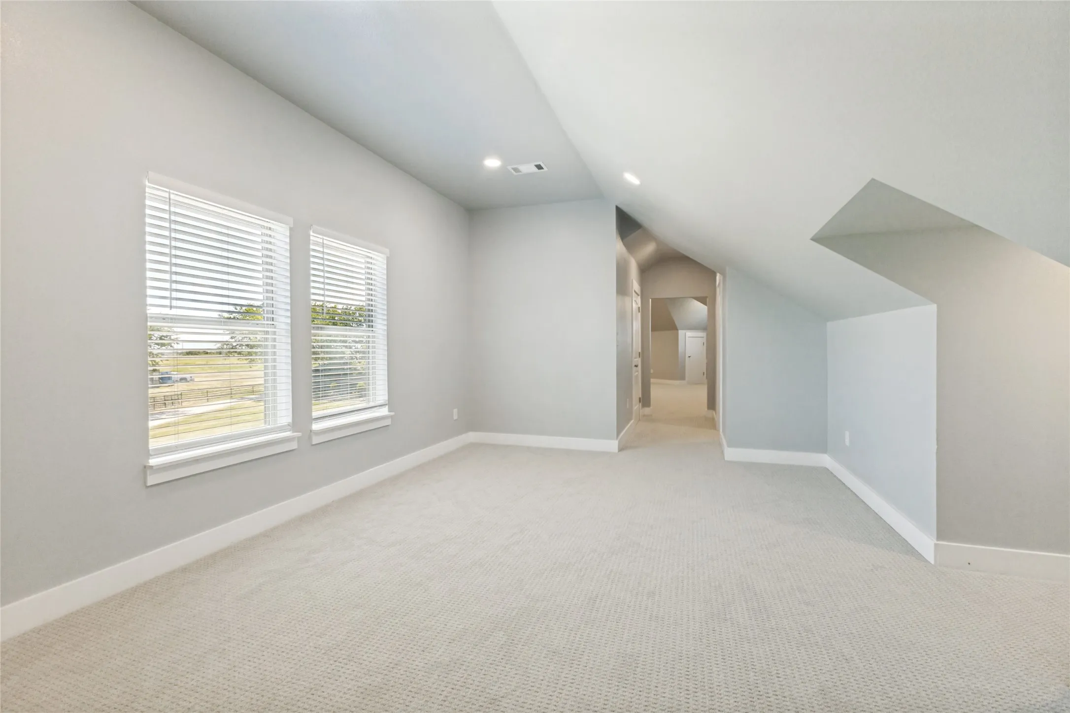 Carpeted room featuring multiple windows with blinds, recessed lighting, and a neutral color palette