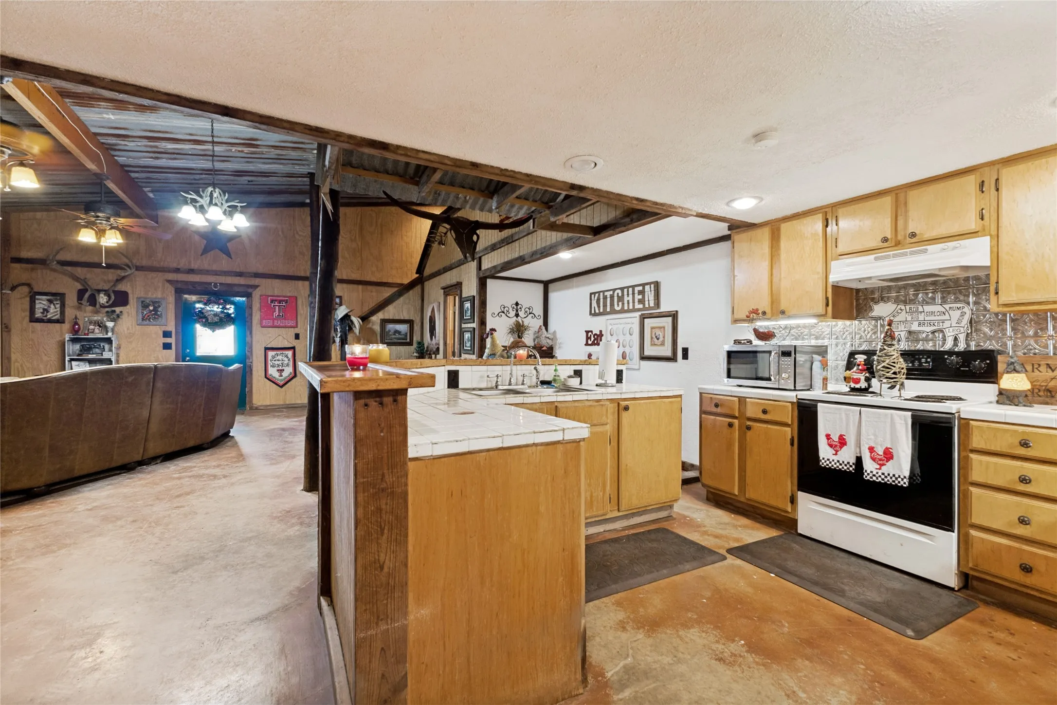 Open-concept living space with exposed wood beams and a corrugated metal ceiling accent