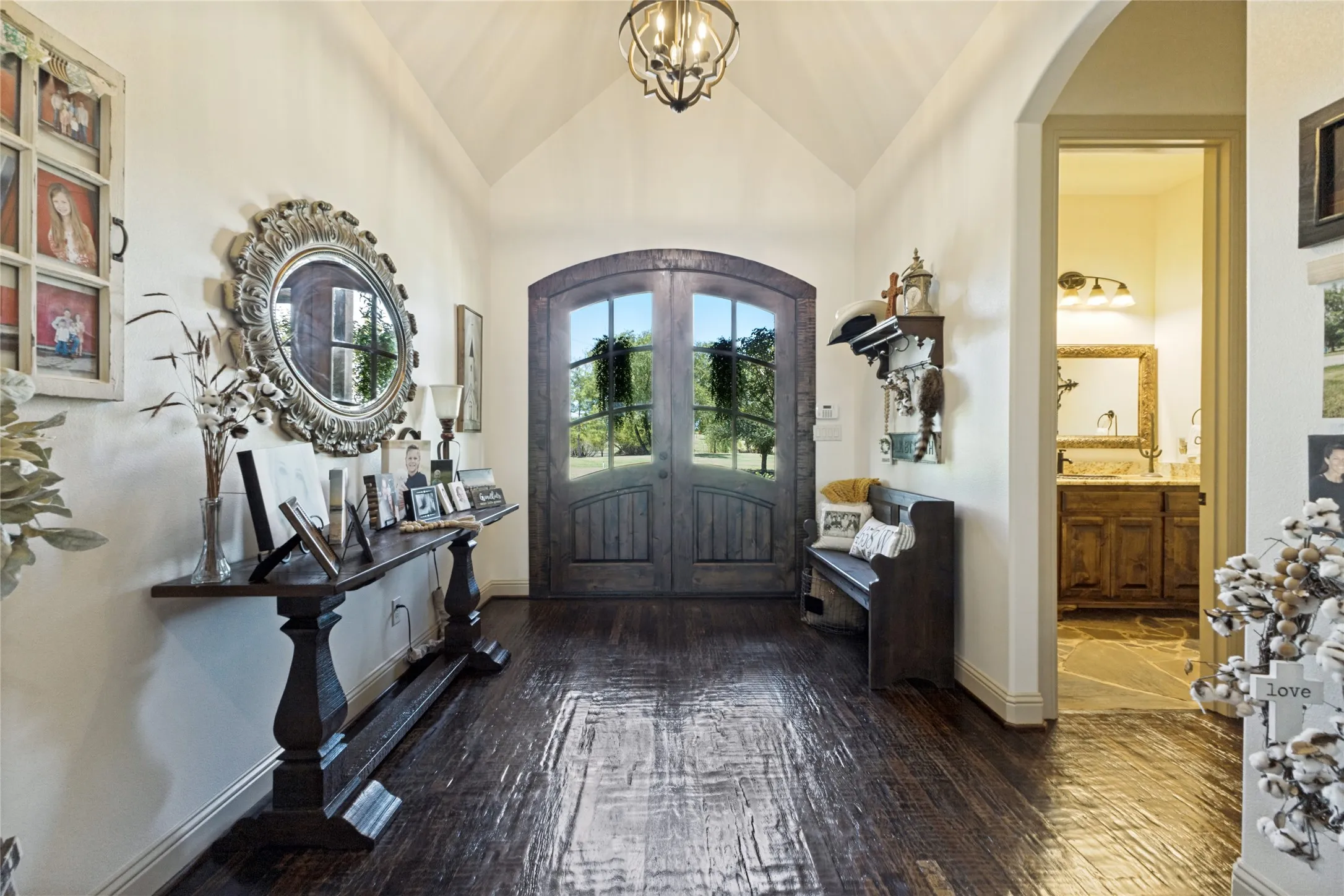 Arched double entry doors, wood-finish flooring, vaulted ceiling, and an arched hallway entry