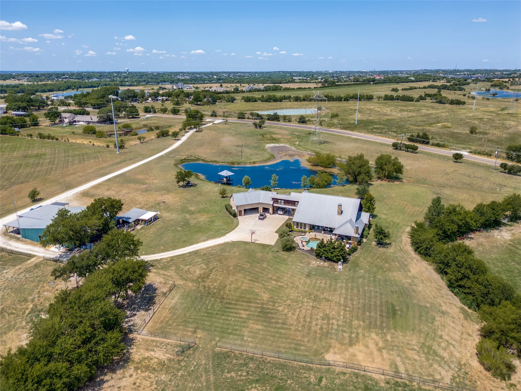 Spacious property featuring a large residence, detached structures, a private pond with a dock, and an outdoor pool