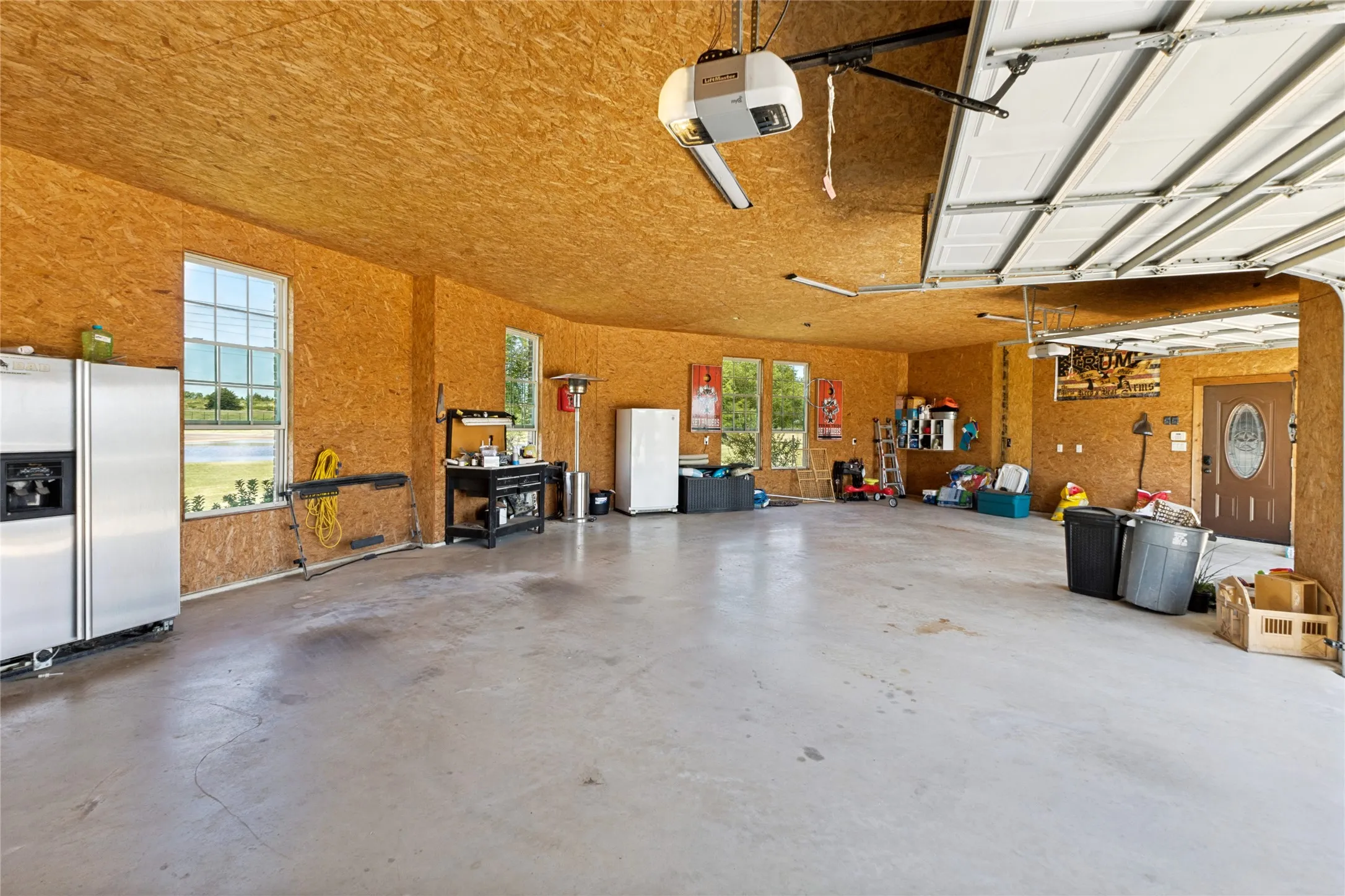 Spacious garage featuring a concrete floor, exposed wood-finish walls and ceiling, and multiple windows
