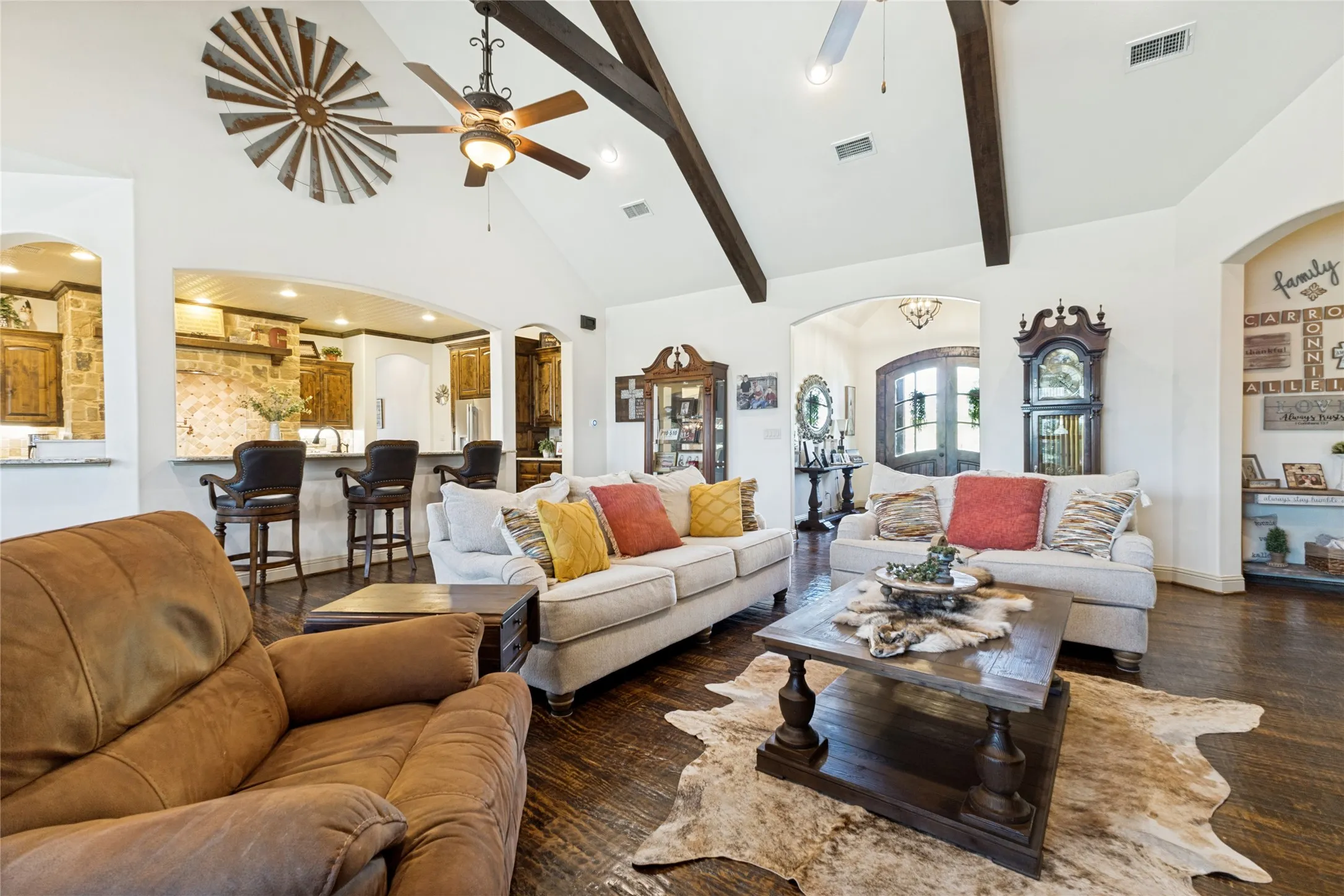 Vaulted ceiling with exposed wood beams, wood-finish flooring, recessed lighting, and an arched doorway