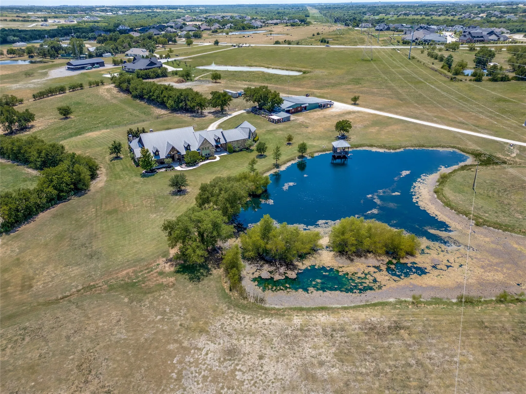 Expansive property featuring a large residence, separate outbuilding, private pond with a dock, and extensive landscaped grounds