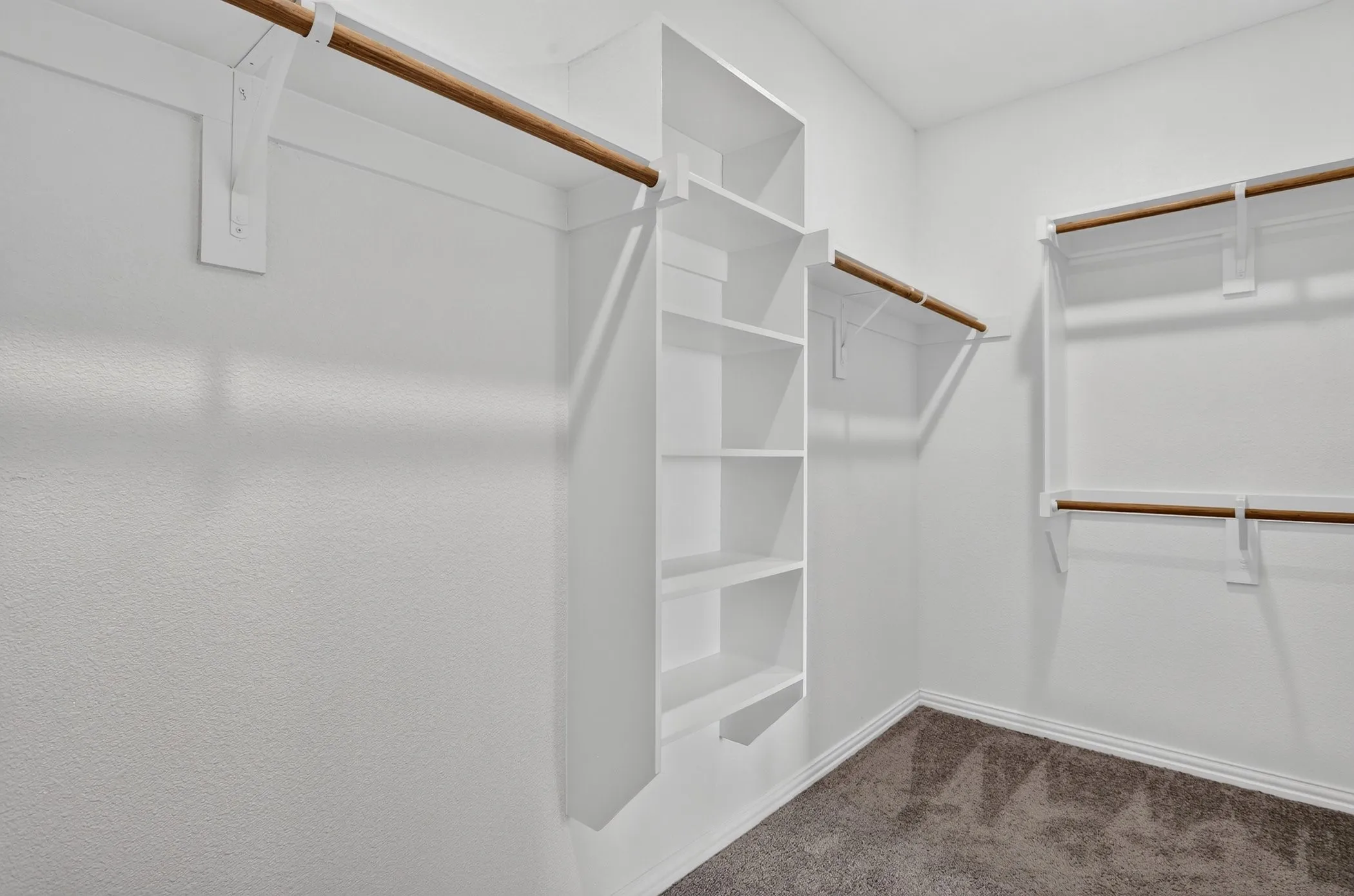 Wall-mounted wood rods, built-in shelving, white trim, and gray carpet flooring