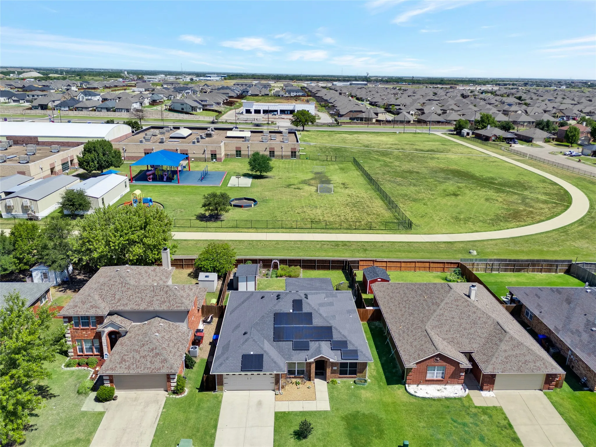Community view of the 2812 Spencer Circle with the School in the background.  The fence has a gate for easy entrance to the school.
