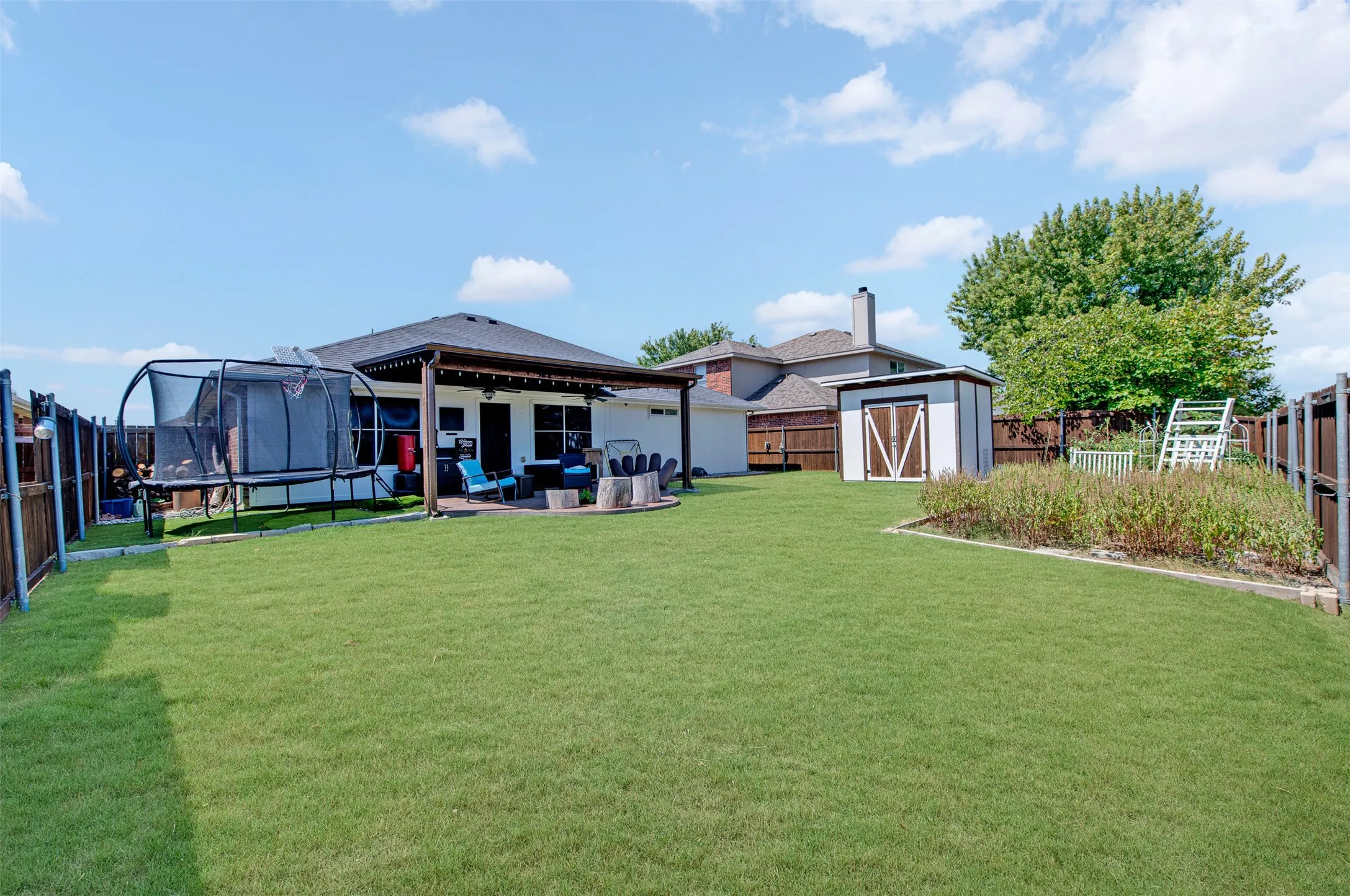 Backyard with extended patio covered with pergola, storage shed on concrete foundation, and garden space