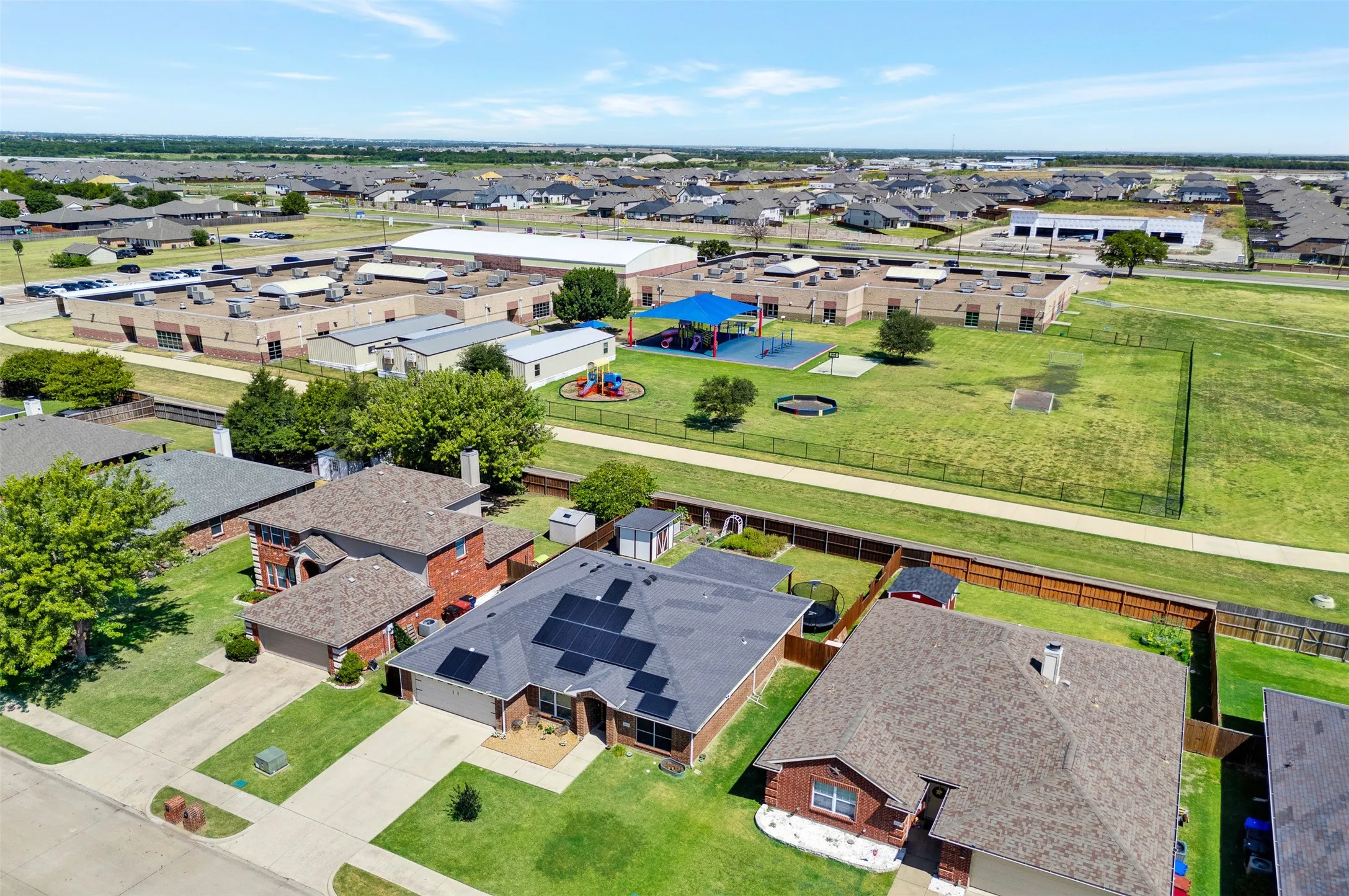 Community view of the 2812 Spencer Circle with the School in the background.  The fence has a gate for easy entrance to the school.