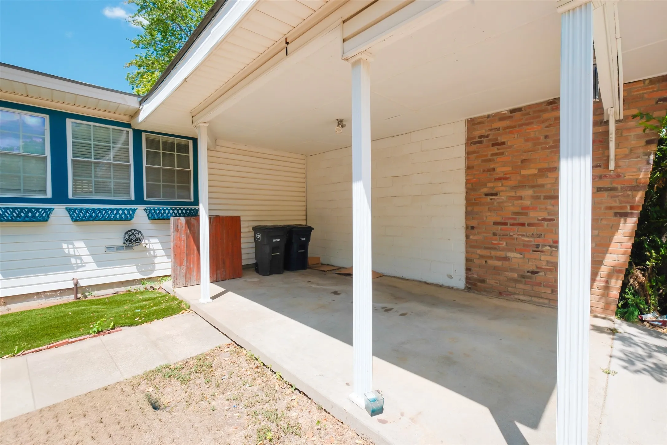 Covered concrete patio featuring brick and horizontal siding accents