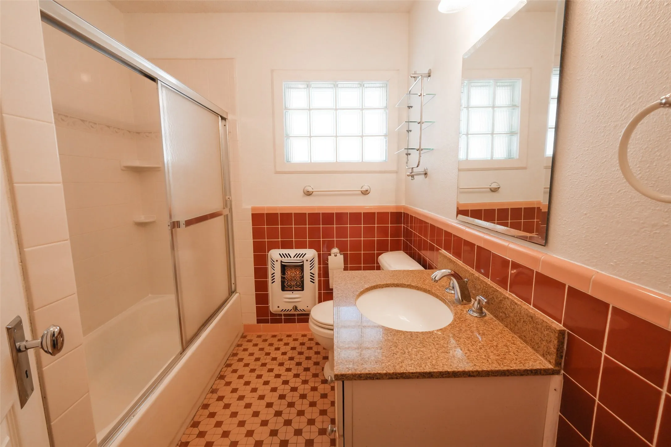 Sliding glass shower enclosure, vanity with integrated sink, polished chrome fixtures, and tiled flooring