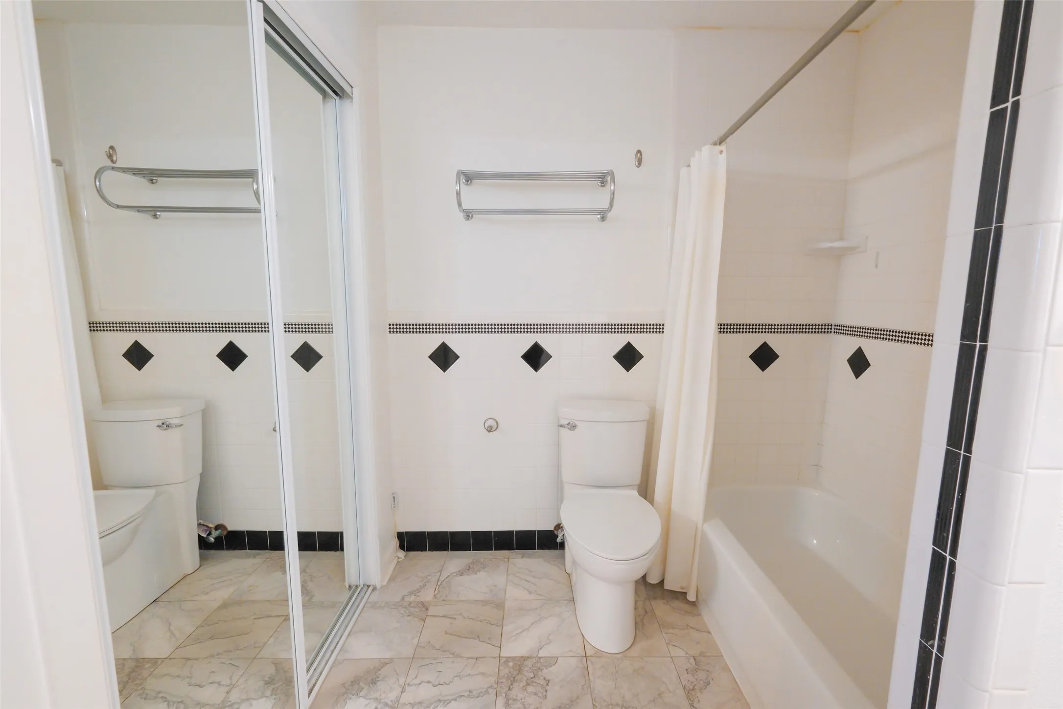 Bathroom featuring a tub/shower combination, white toilet, and patterned wall tile