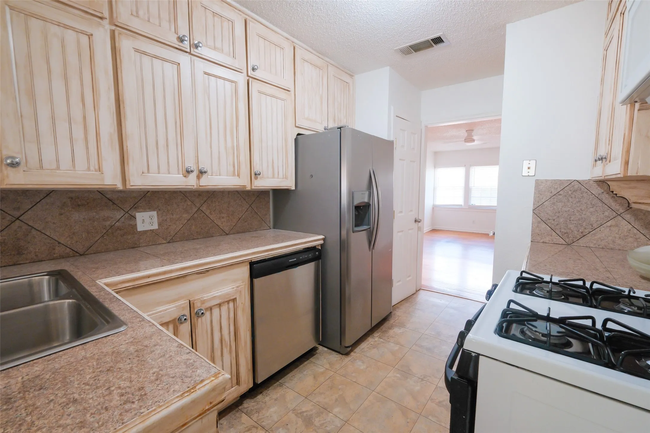 Kitchen with panel-style cabinetry, stainless steel dishwasher, stainless steel refrigerator, and dual basin sink