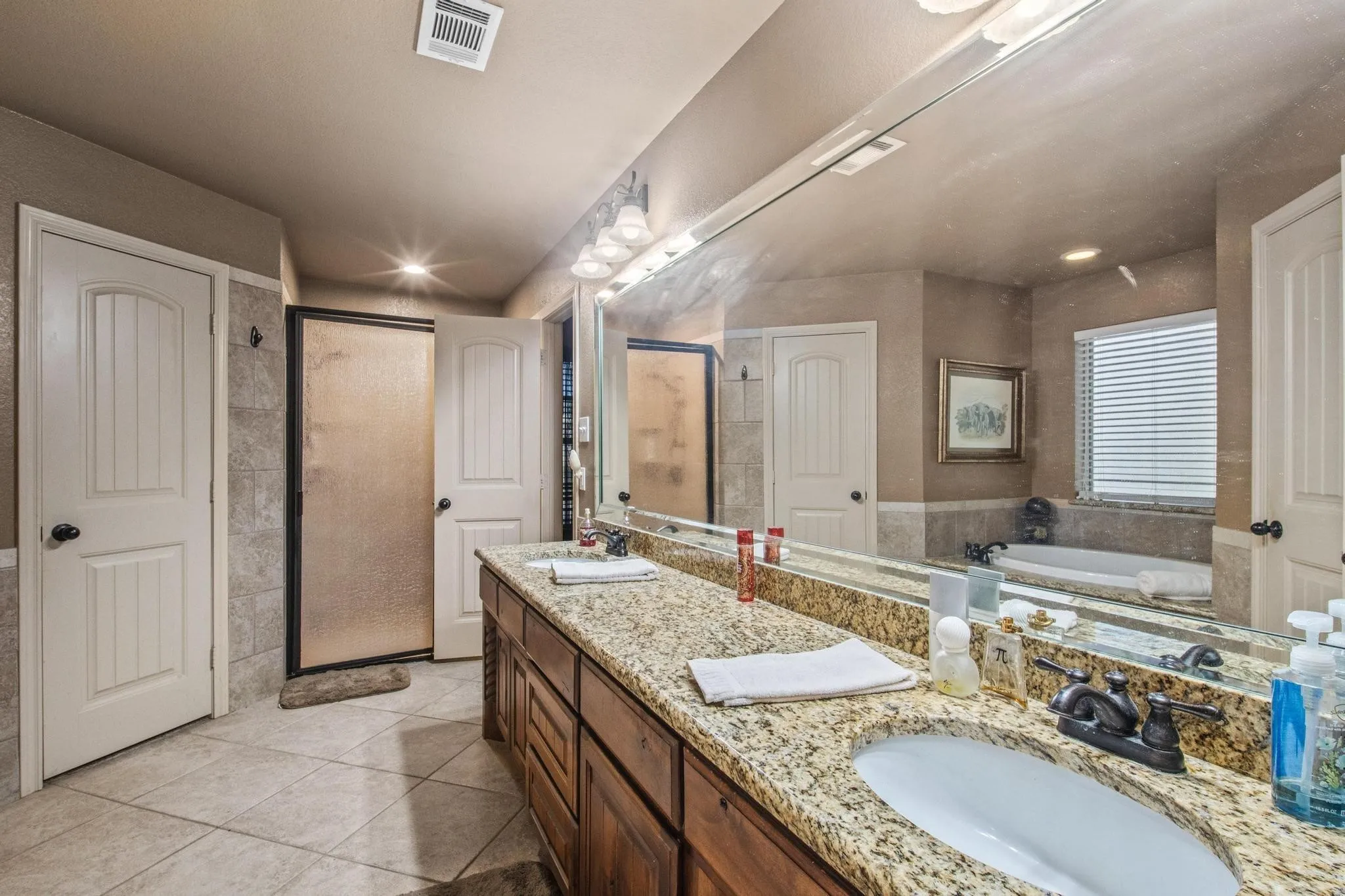 Dual sinks set in a granite-finish countertop with a wood-finish vanity