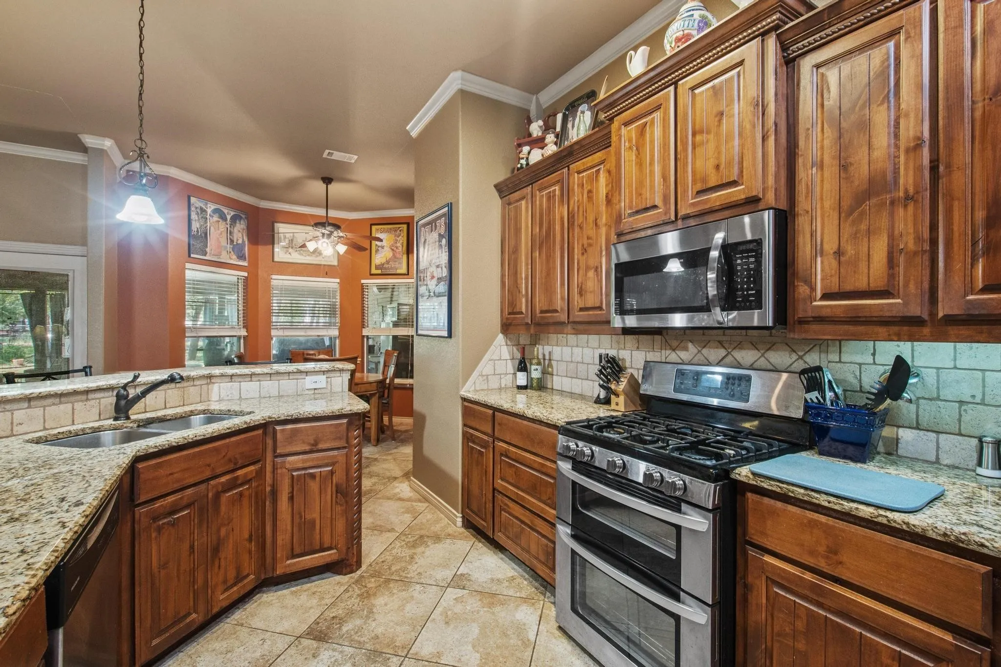 Kitchen featuring wood cabinetry, granite countertops, stainless steel appliances, a tile backsplash, and tile flooring