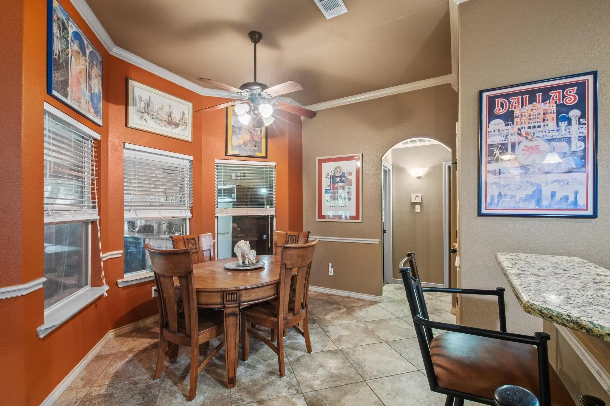Recessed lighting, ceiling fan with light fixture, tile flooring, arched doorway, and built-in breakfast bar with stone-look countertop