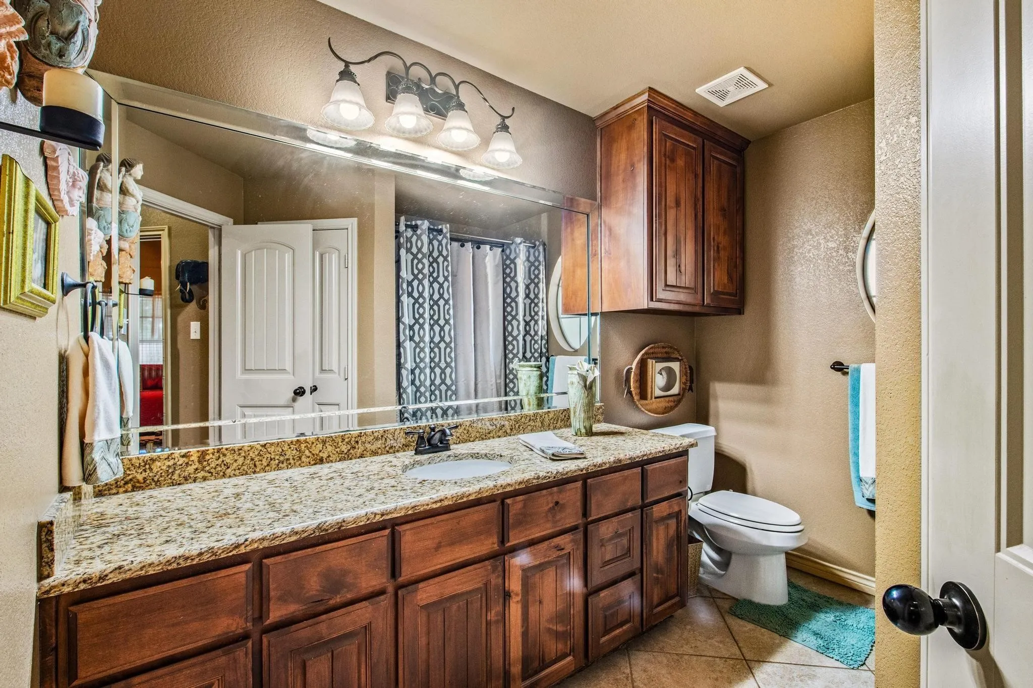 Wood-finish vanity with ample storage, integrated sink, and stone-finish countertop