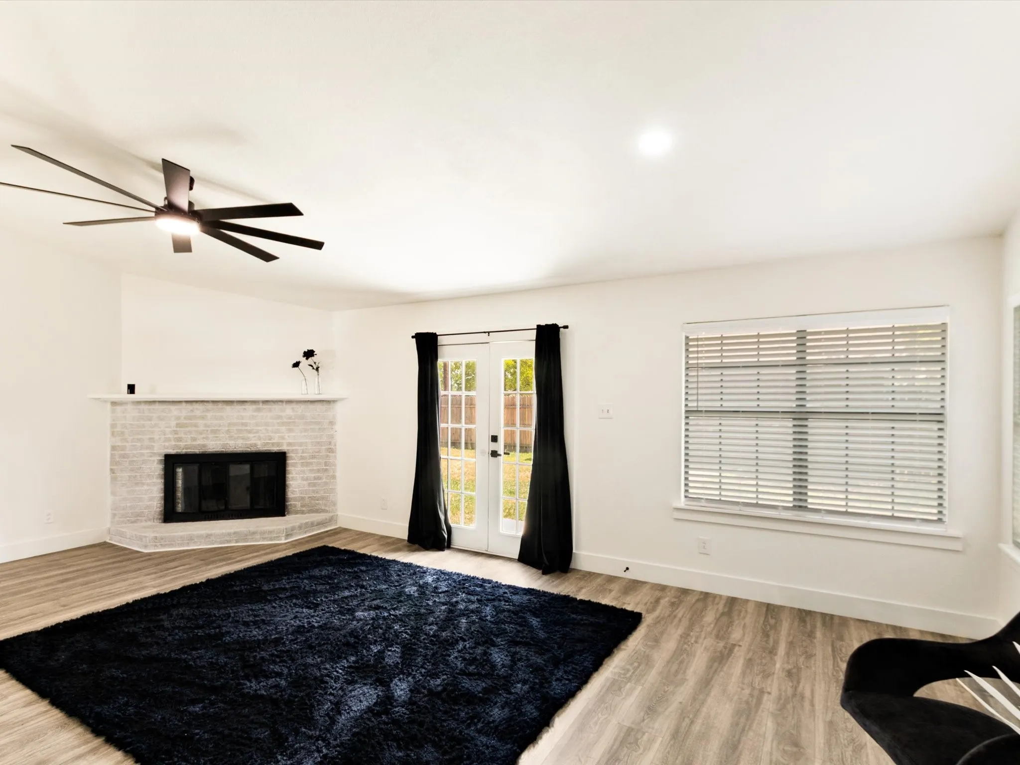 Spacious living area featuring a corner fireplace, wood-finish flooring, and French doors
