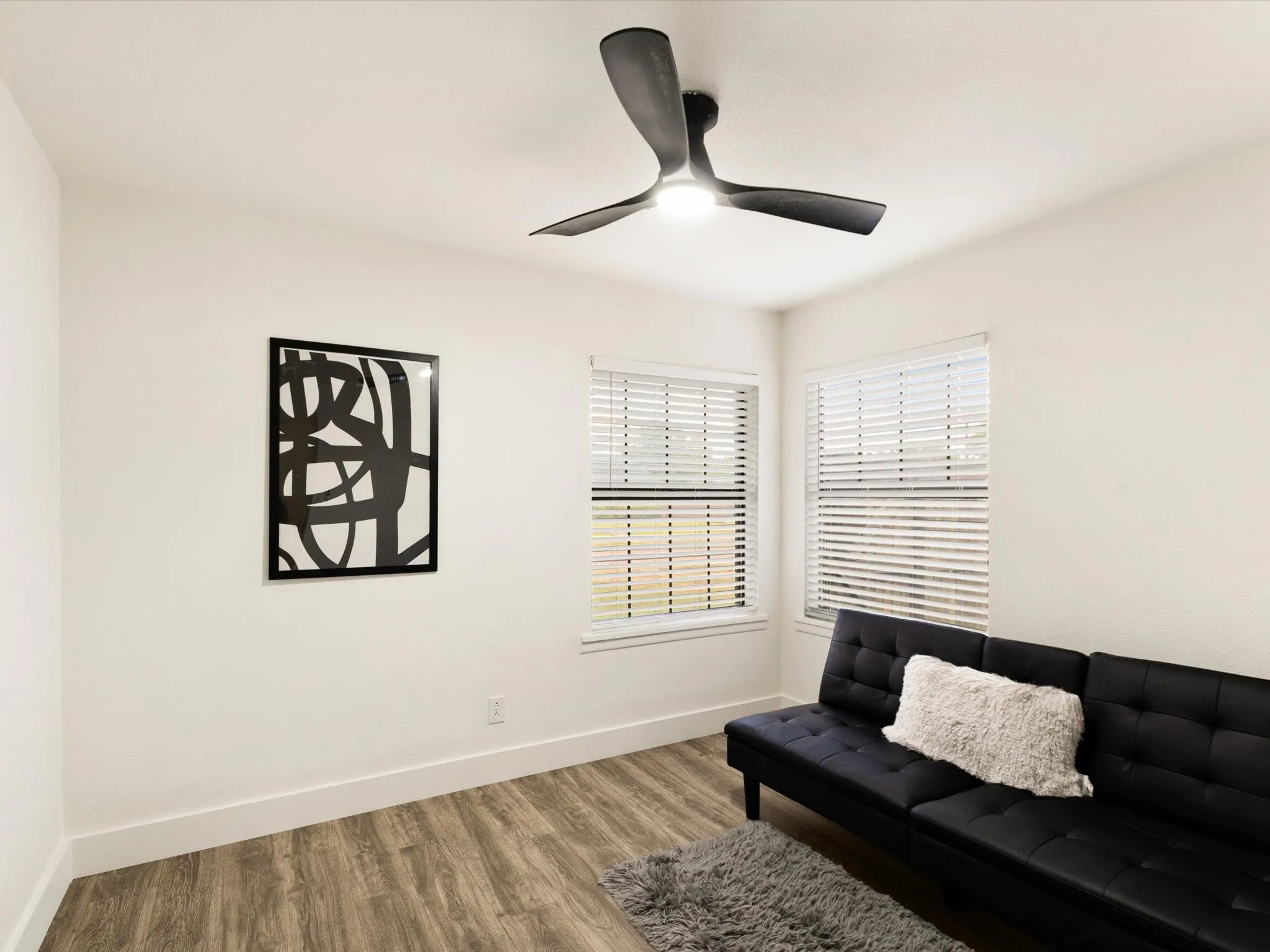 Recessed ceiling light with a modern ceiling fan, two windows with blinds, and wood-finish flooring