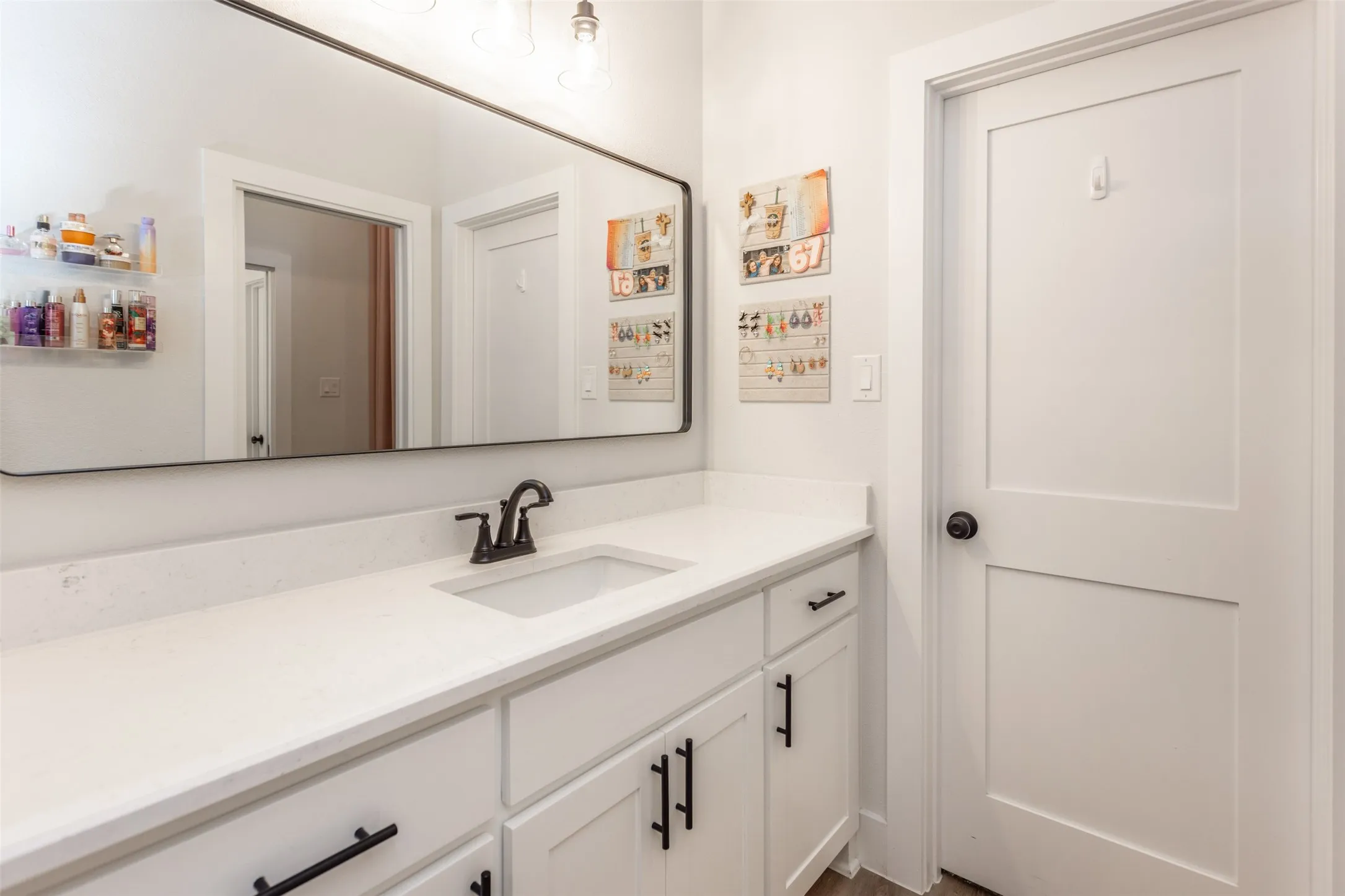 White vanity with integrated sink, black faucet, and a large wall-mounted mirror