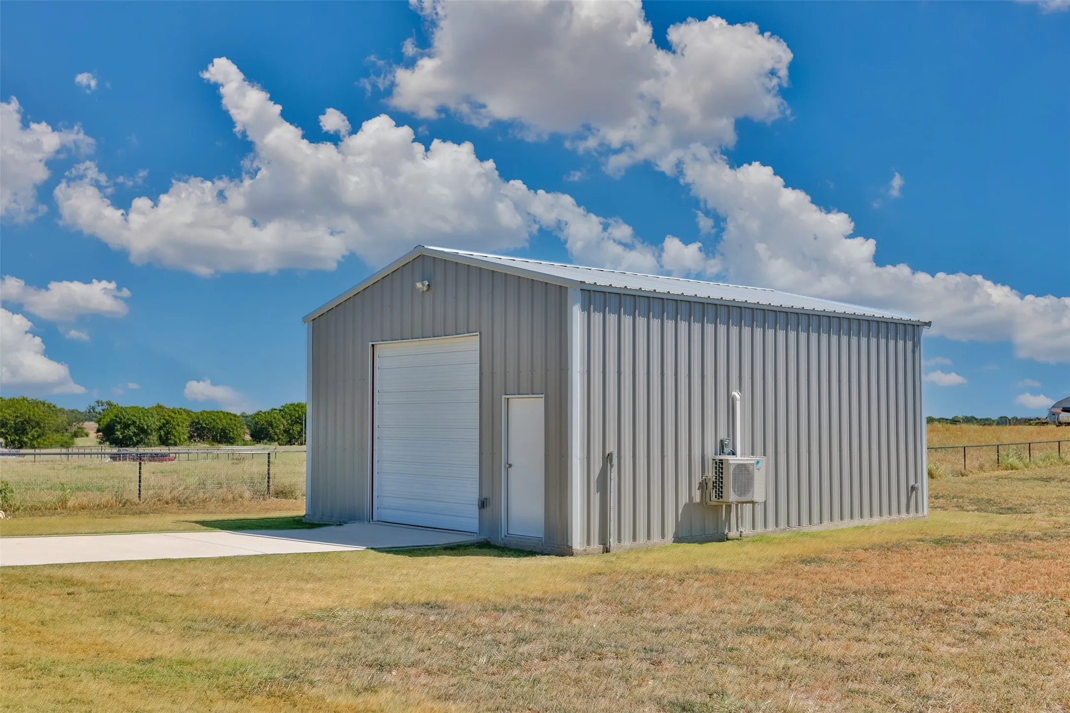 Metal-sided structure featuring a pitched roof, roll-up door, and separate entry door