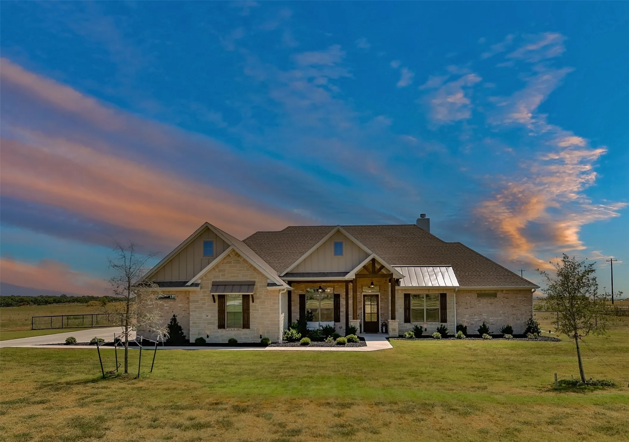 Stone and siding exterior with a shingled roof, featuring a covered entry, decorative shutters, and an attached two-car garage