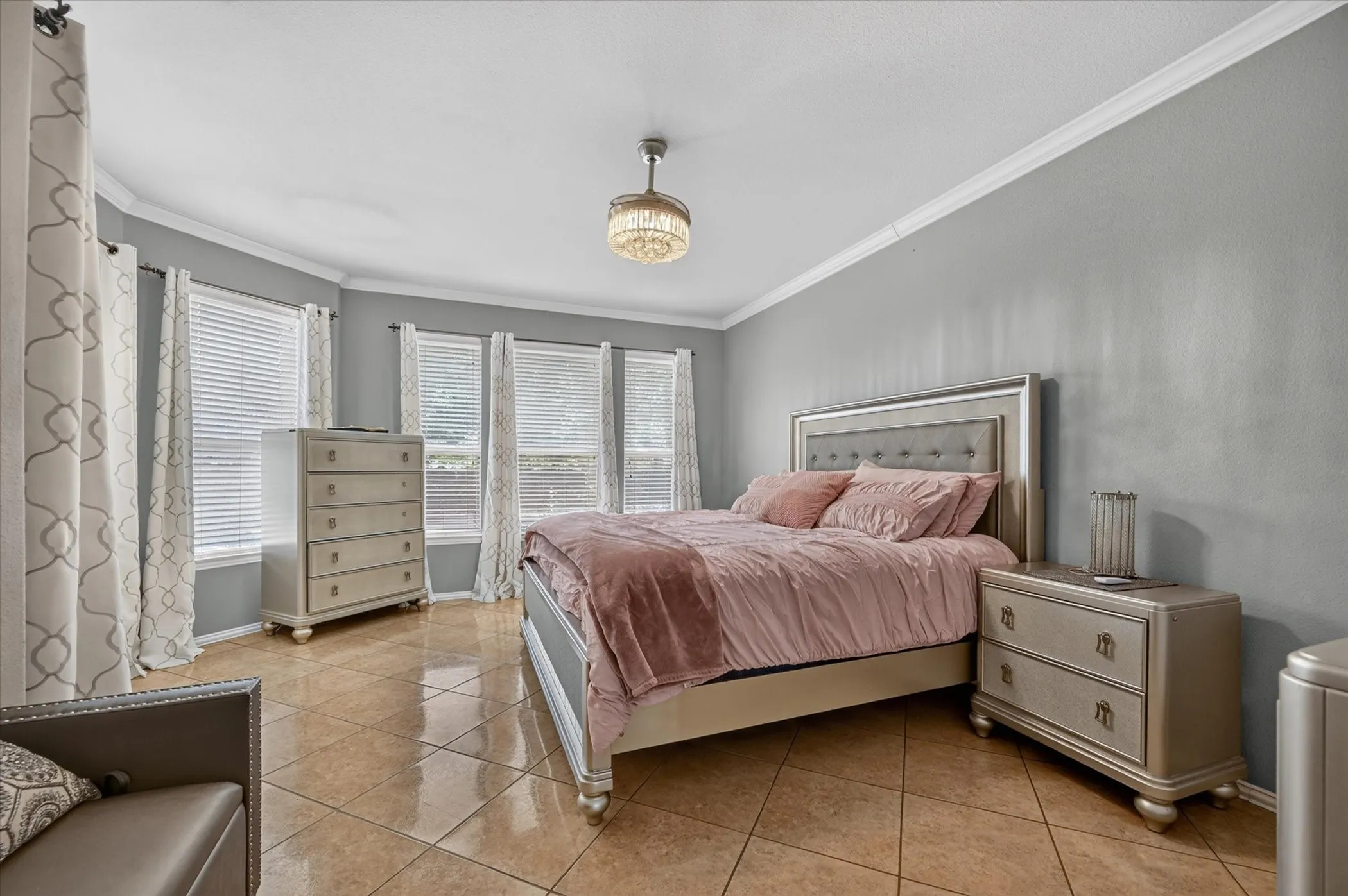 Bay window with multiple windows, crown molding, ceiling fan with integrated lighting, and tile flooring