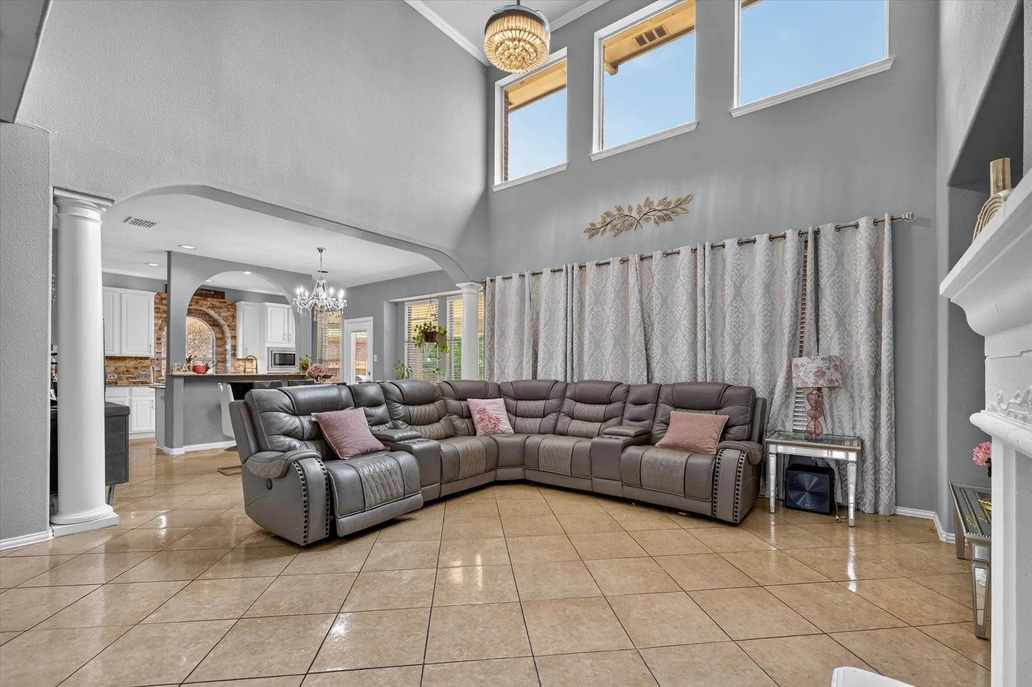 Two-story ceiling, arched doorways, tiled flooring, upper-level windows, and a built-in fireplace