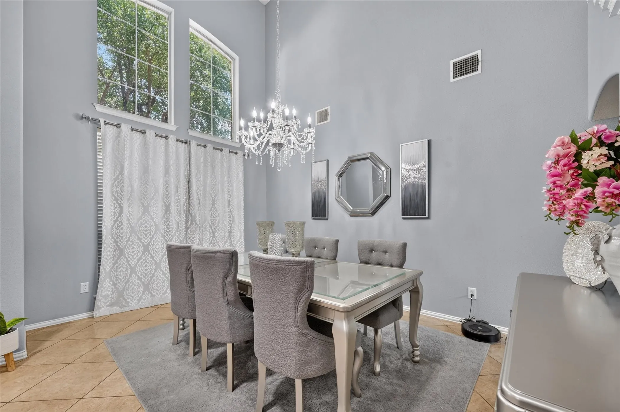 Vaulted ceiling with a chandelier, tile flooring, and tall windows