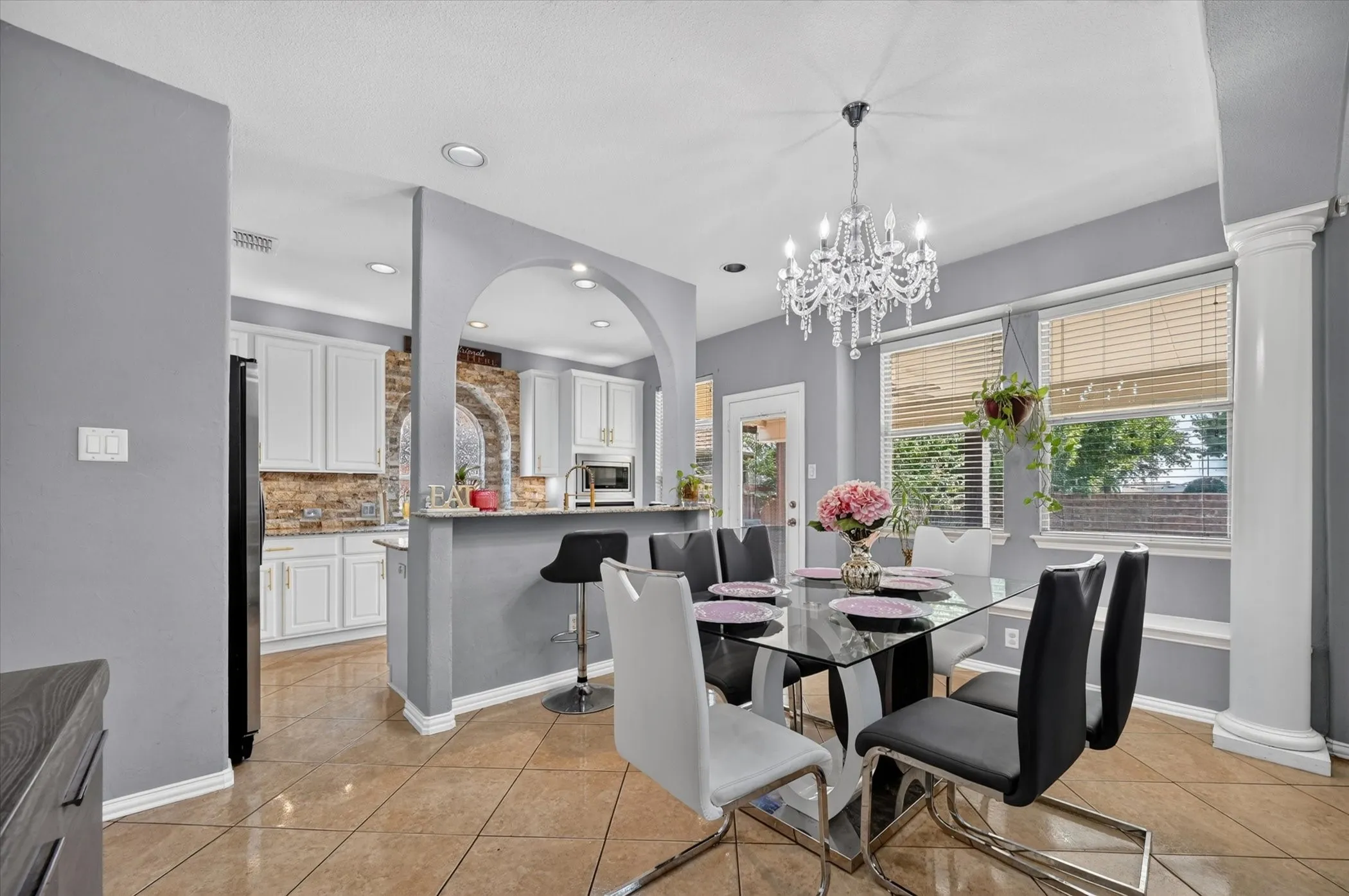 Dining area with a crystal chandelier, tile flooring, and multiple windows