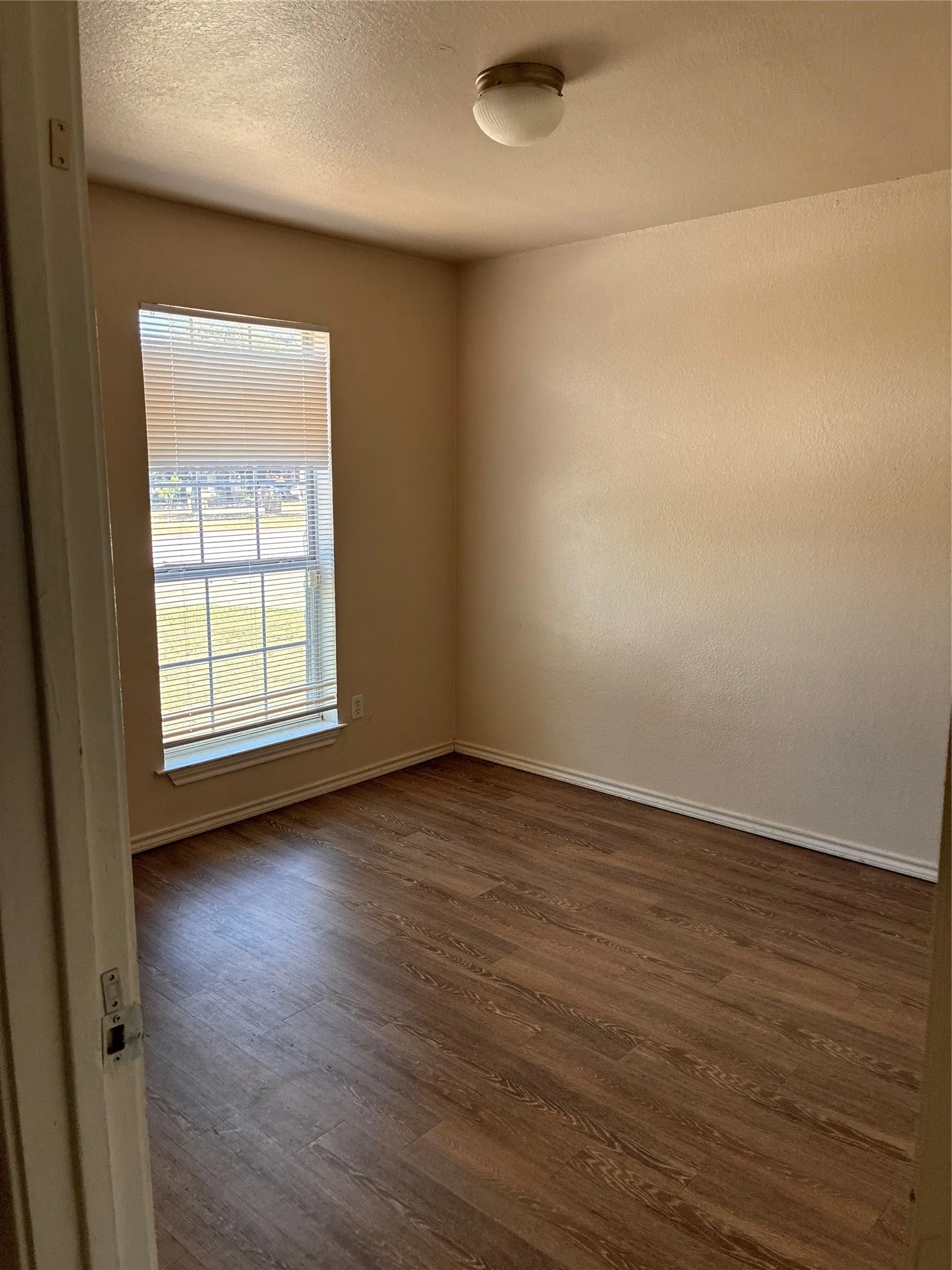 Wood-finish flooring, neutral wall tones, and a window with horizontal blinds