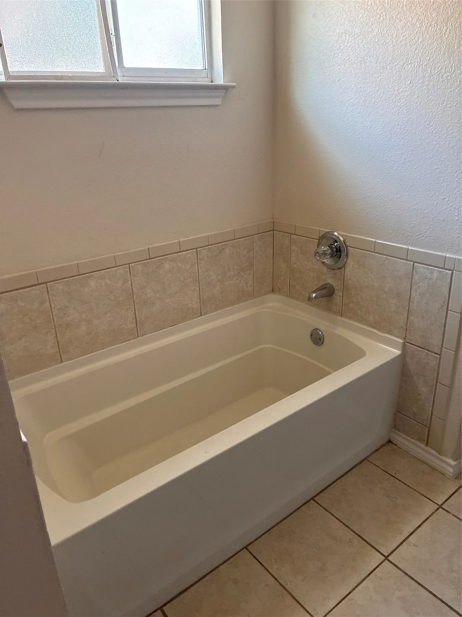 Built-in bathtub with a tile surround and chrome fixtures