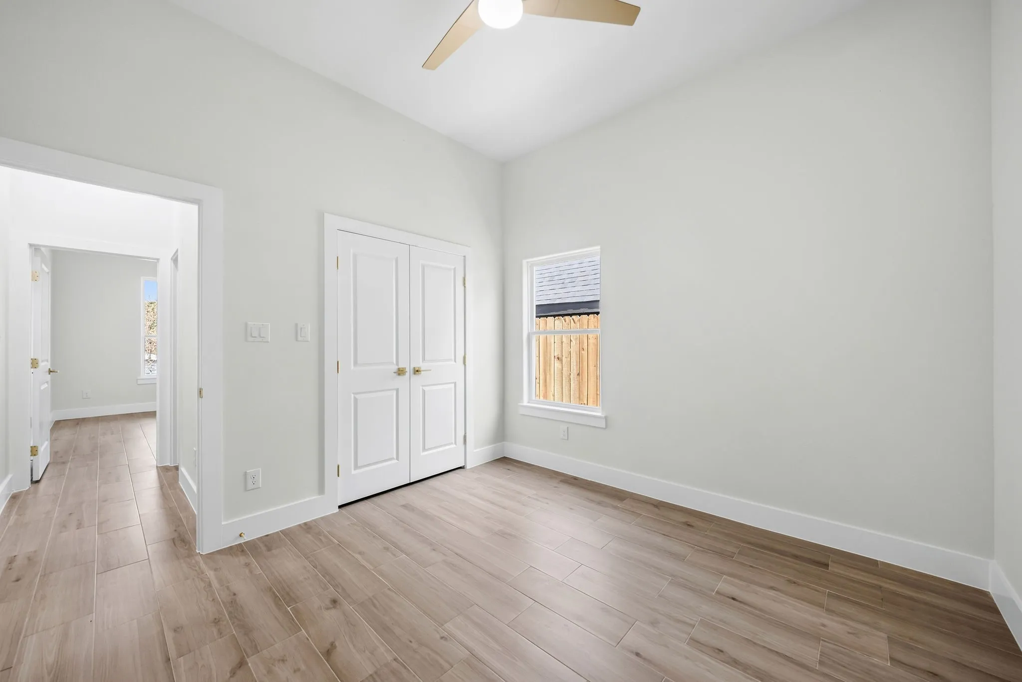 Vaulted ceiling, wood-finish flooring, white walls, double-door closet, ceiling fan with light fixture