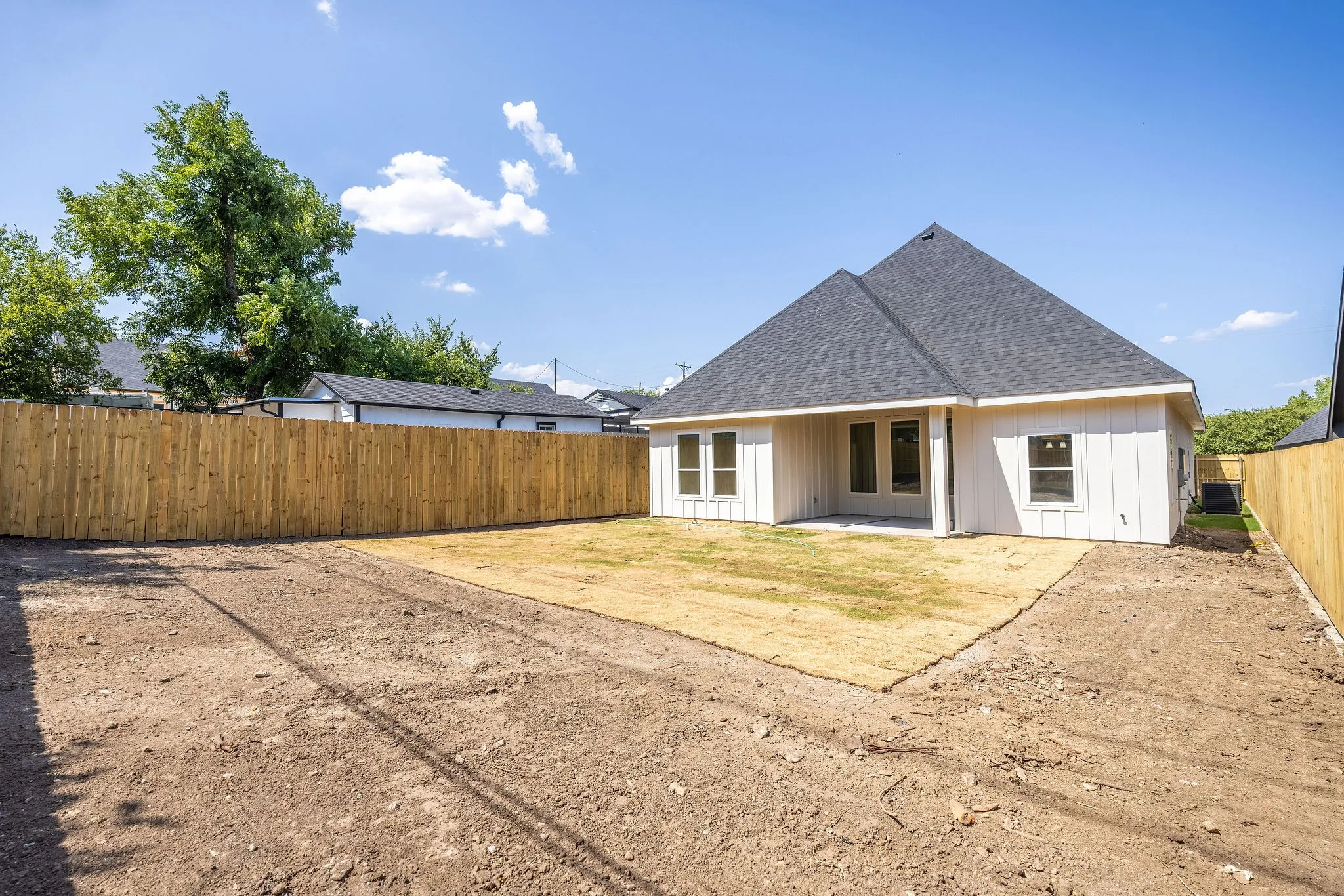 Charming single-story residence featuring a peaked roof with dimensional shingle detailing, white exterior siding, and multi-pane windows