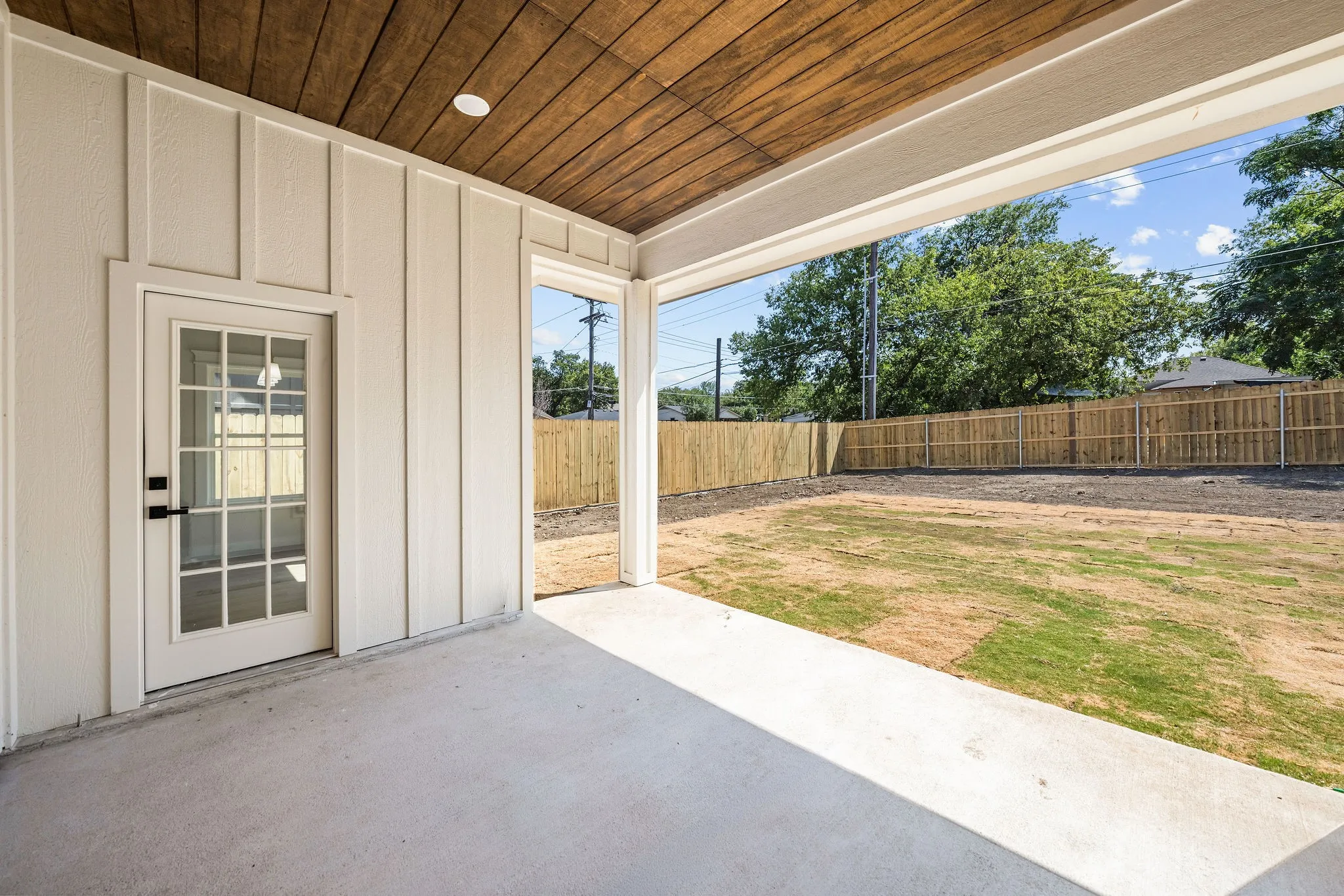 Covered patio featuring a wood-panel ceiling, recessed lighting, and board and batten siding
