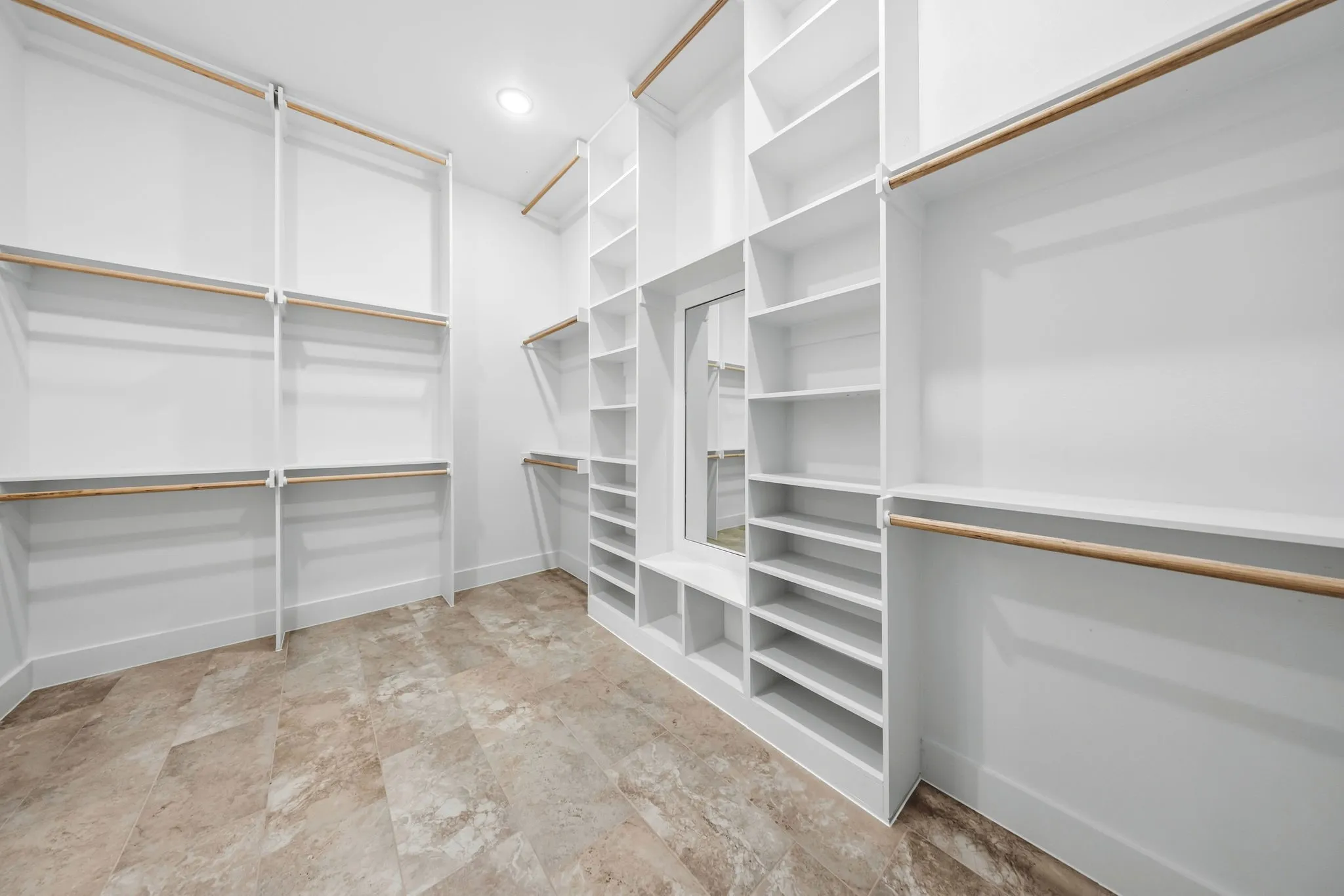 Walk-in closet with extensive built-in shelving, multiple hanging rods, recessed lighting, and a full-length mirror