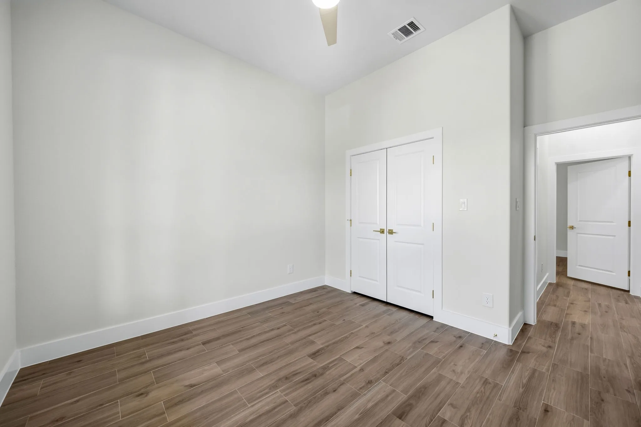 Wood-finish flooring with white baseboards and trim