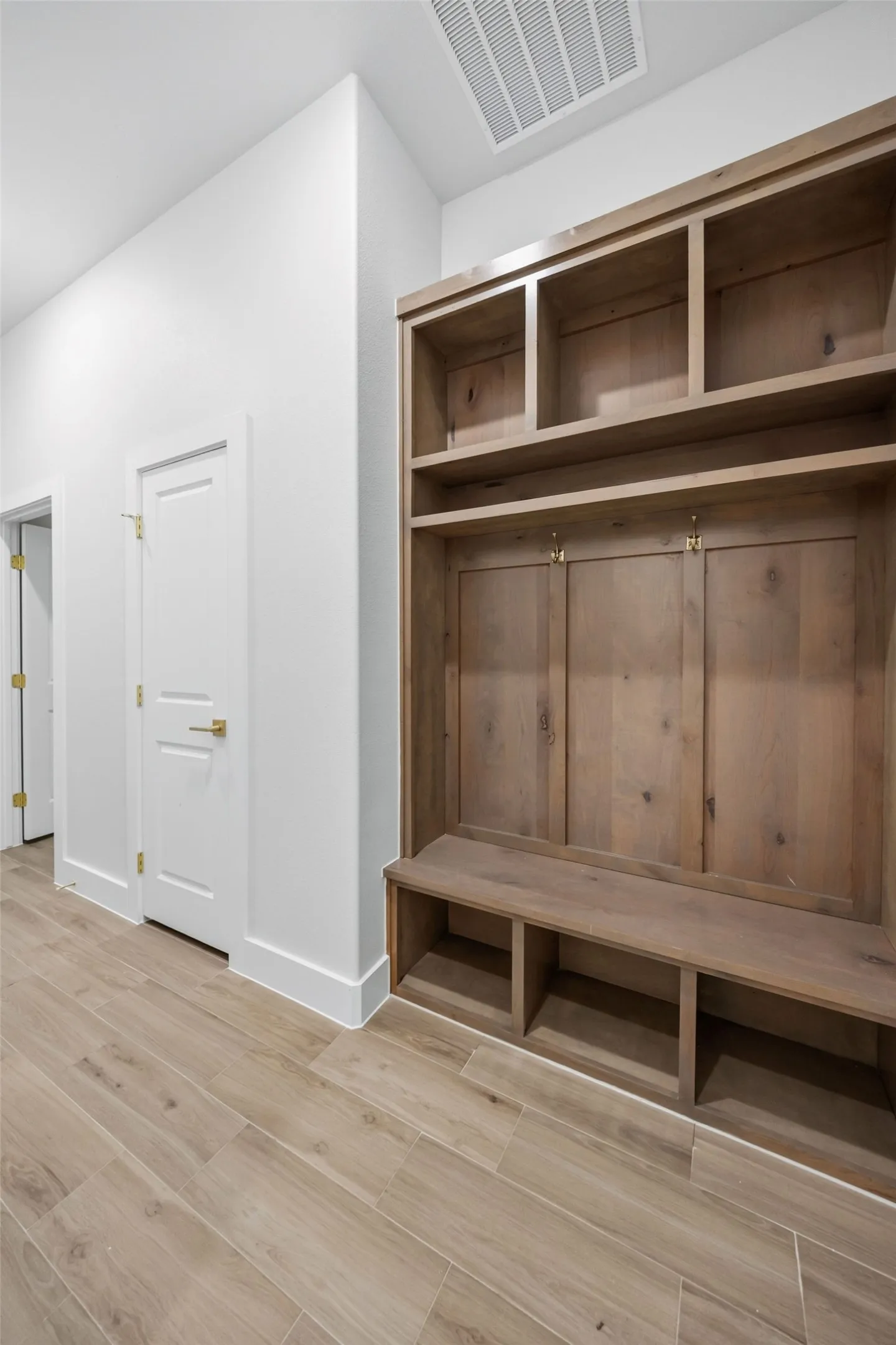 Built-in wood-finish storage unit with a bench and cubbies