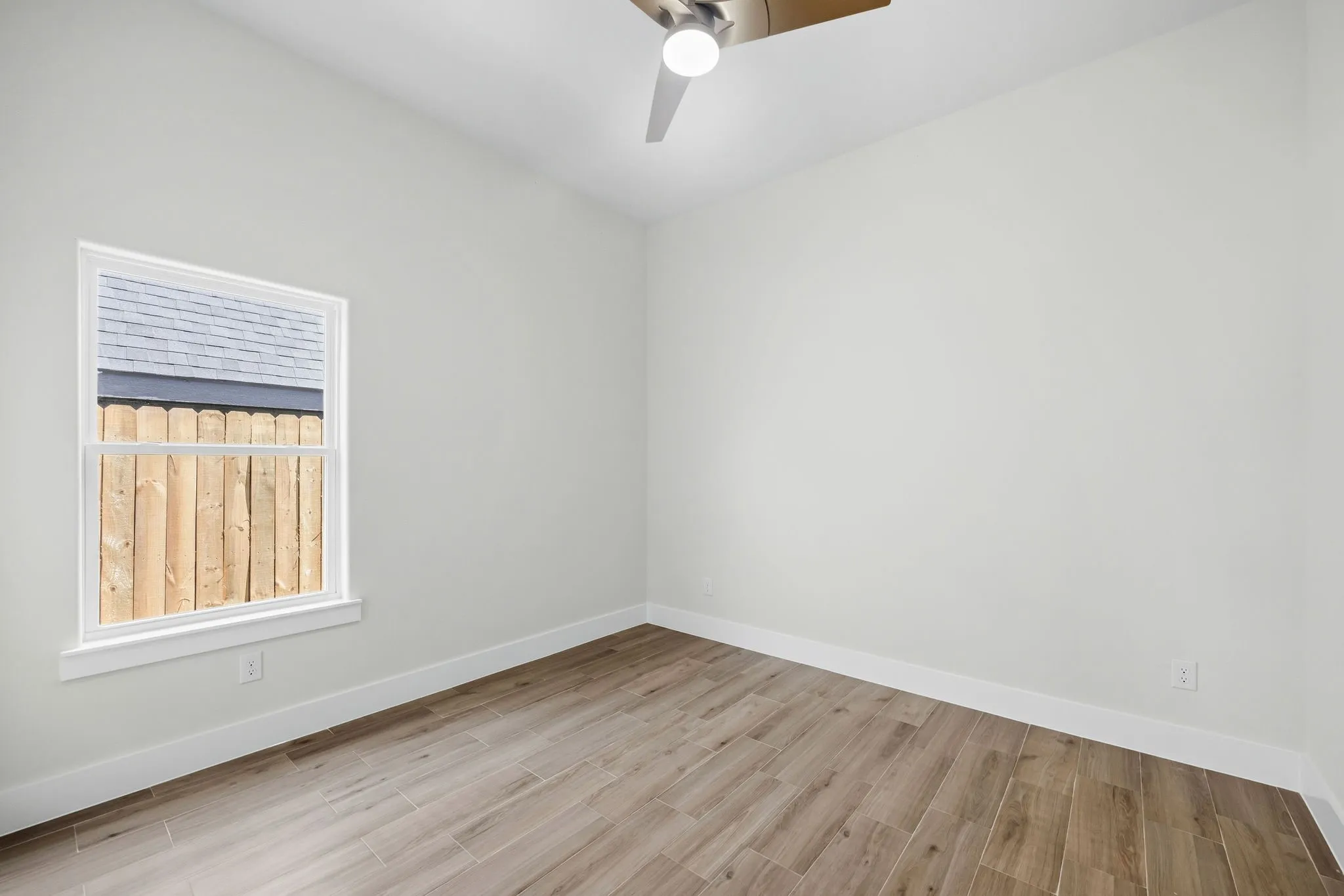 Wood-finish flooring, white walls, and a ceiling fan
