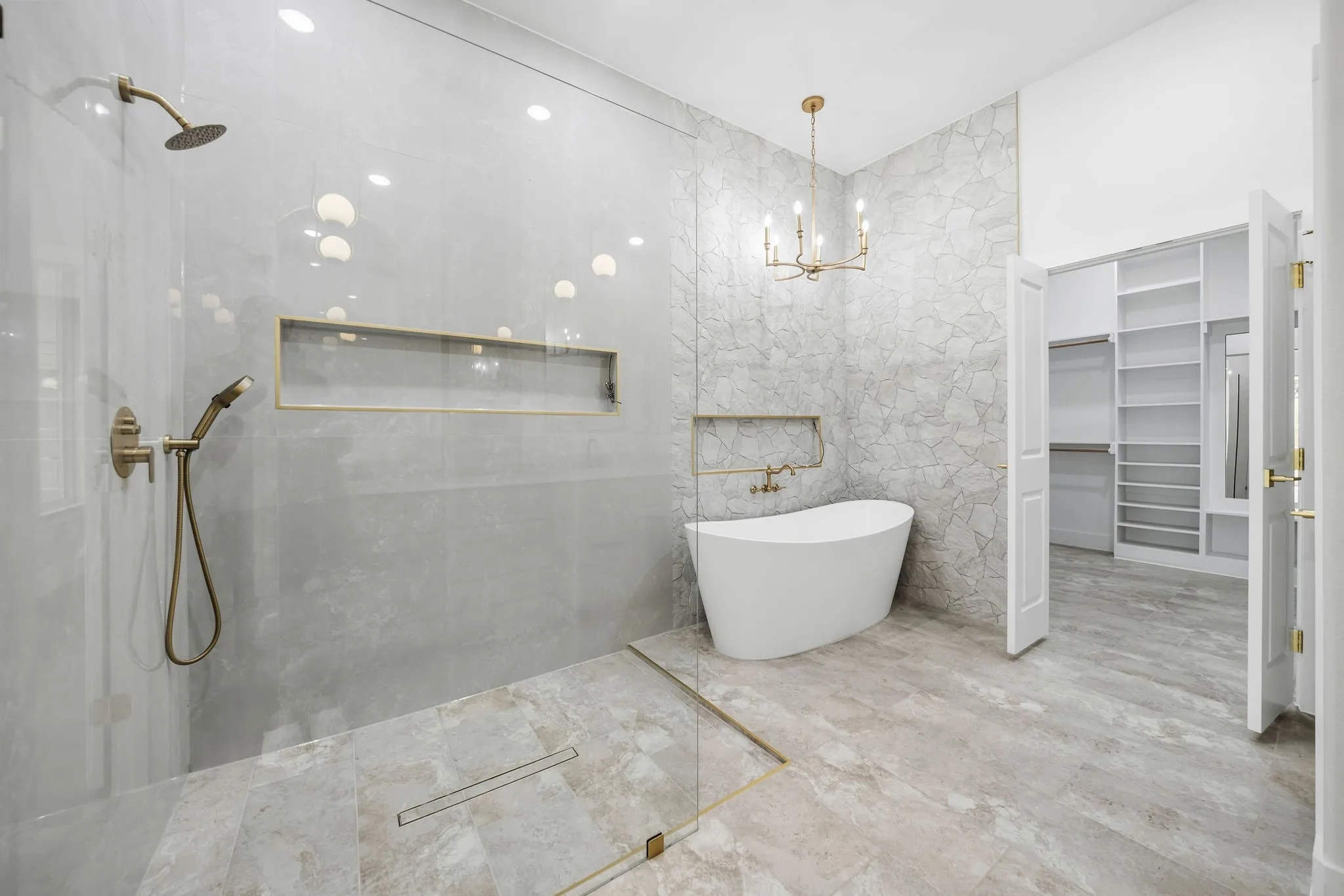 Spacious bathroom featuring a freestanding soaking tub, walk-in shower with glass enclosure, and a gold-toned chandelier