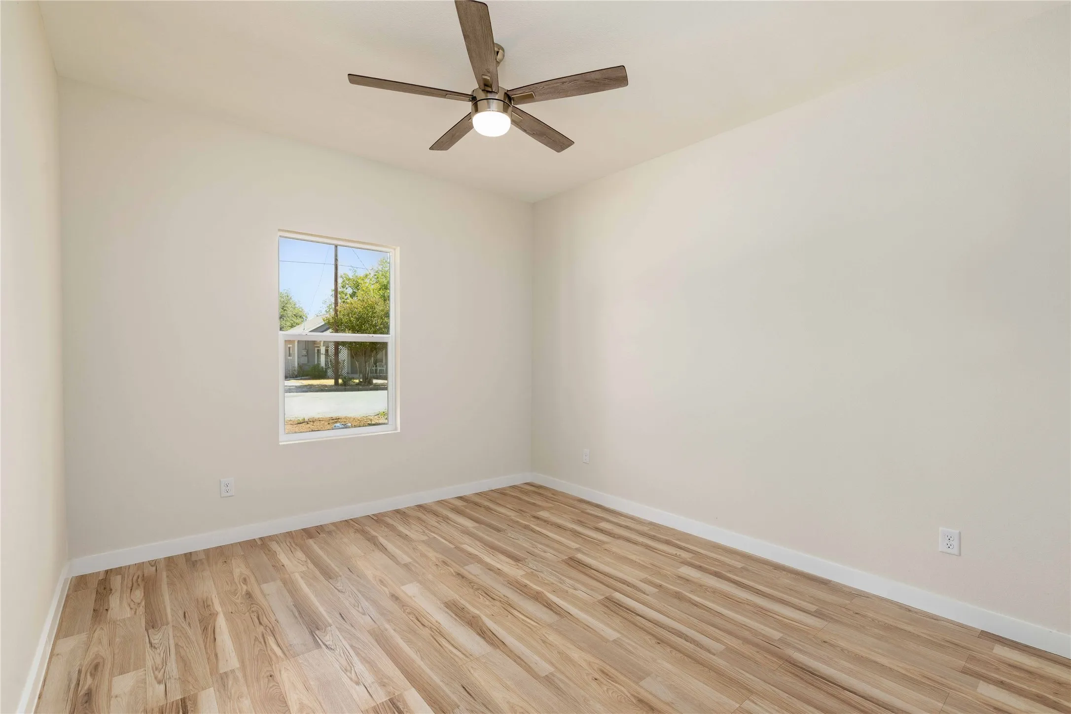 Vaulted ceiling with a ceiling fan, light wood-finish flooring, and a single-pane window