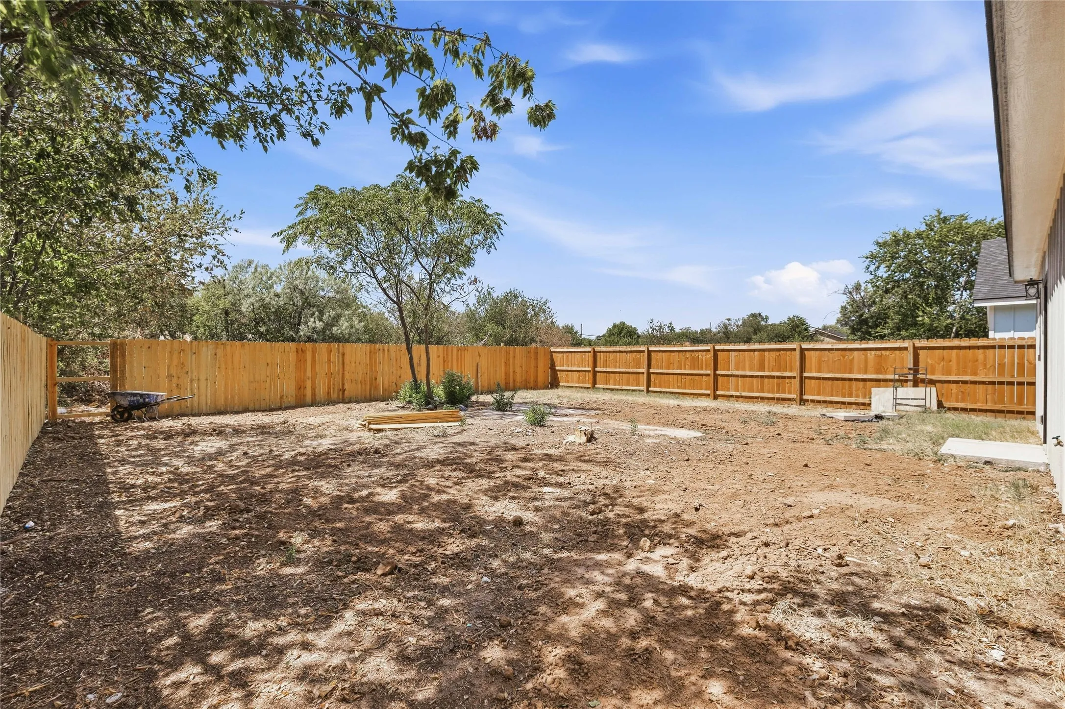Expansive backyard featuring a natural dirt surface, new wood fencing