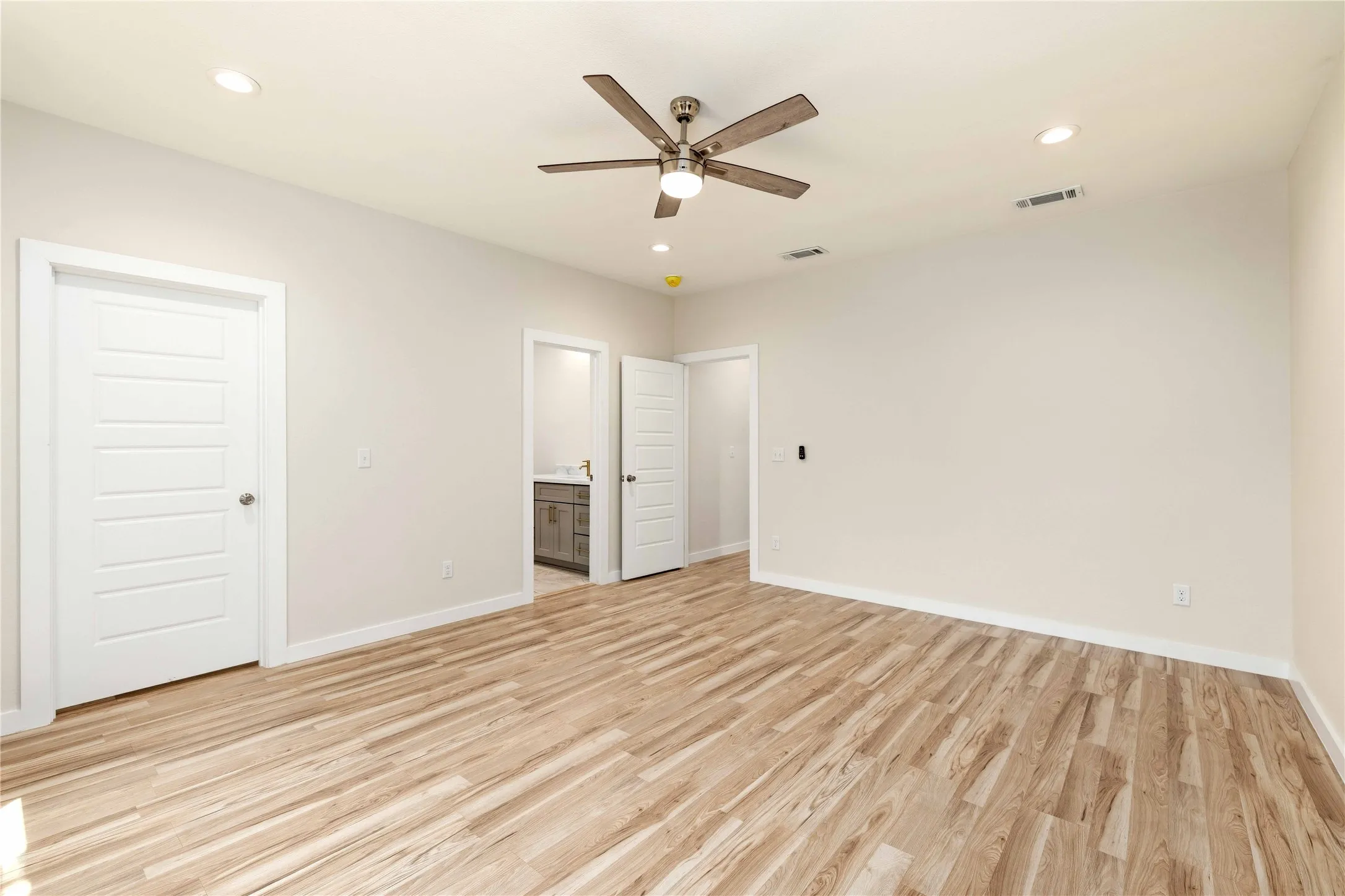 Spacious room featuring wood-finish flooring, recessed lighting, and a ceiling fan