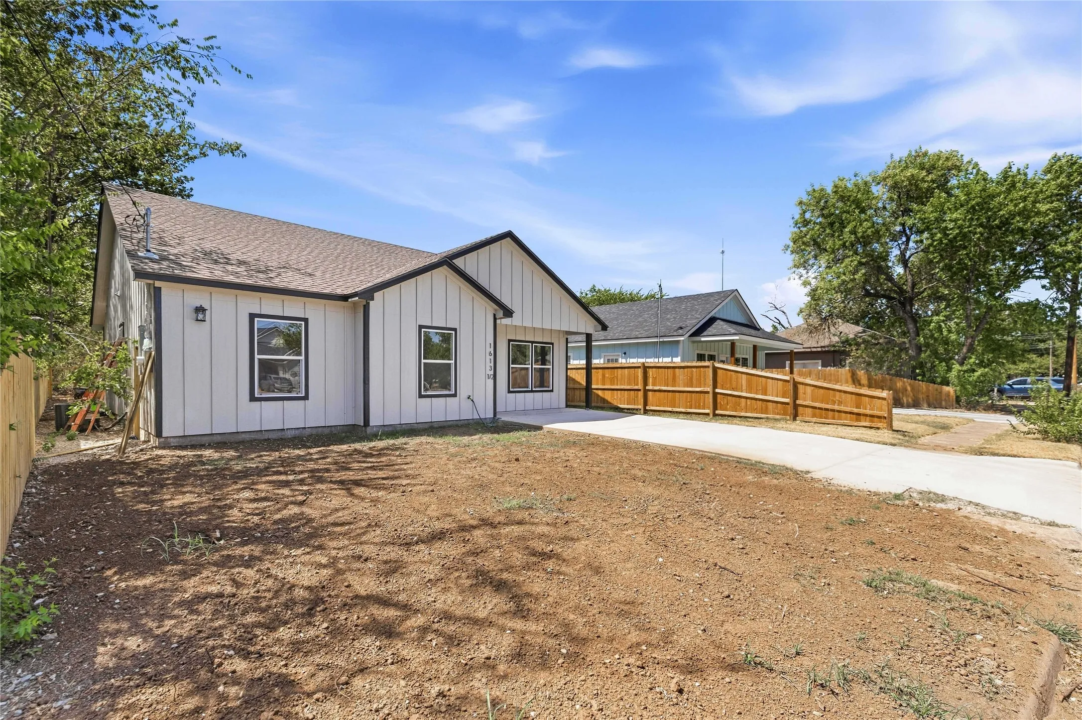 White vertical siding exterior with dark trim, asphalt shingle roof, and a concrete driveway