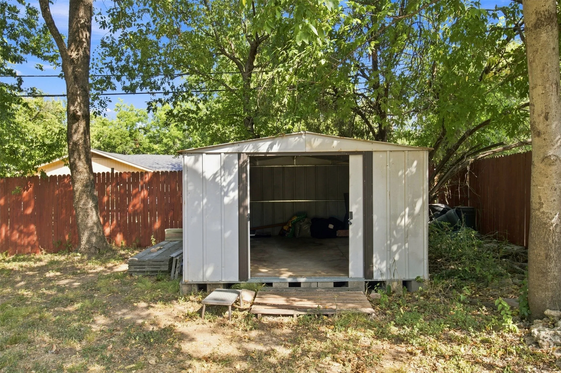 Detached storage shed with open double doors, set on a raised foundation