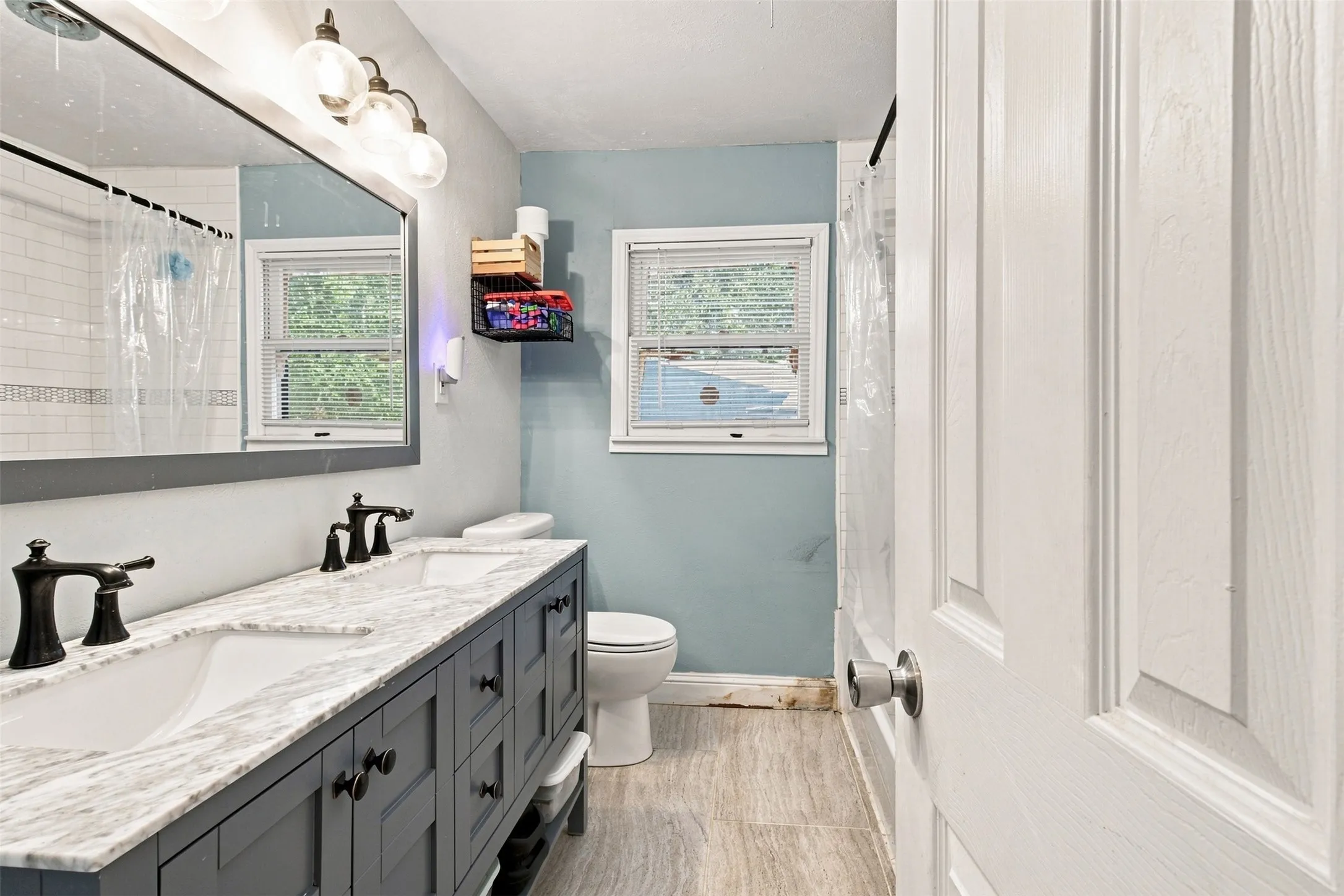 Dual vanity with stone-finish countertop, dark cabinetry, and matte black fixtures