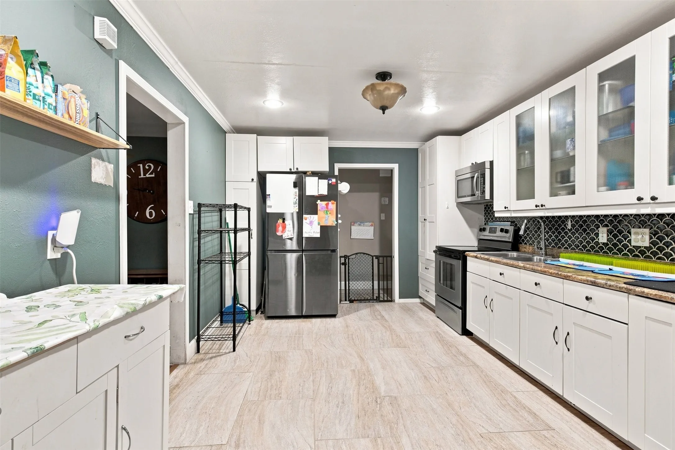 Wood-finish flooring with white cabinetry, stainless steel appliances, and a dark decorative tile backsplash