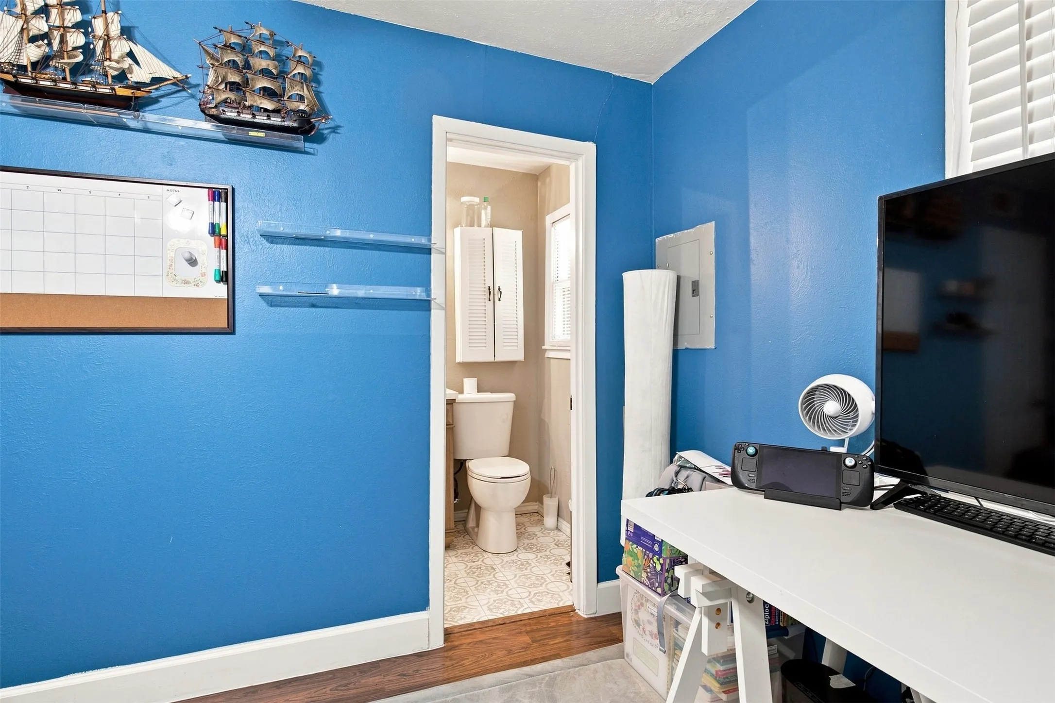 White trim work, wall-mounted shelving, and a wood-finish flooring transition to a tiled room