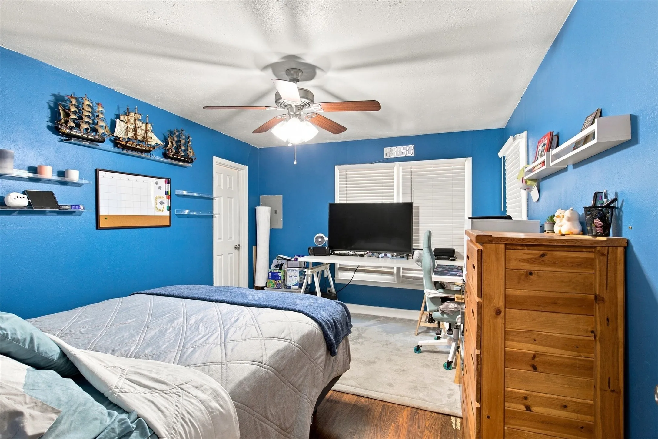 Room featuring wood-finish flooring, a ceiling fan, and a window with blinds