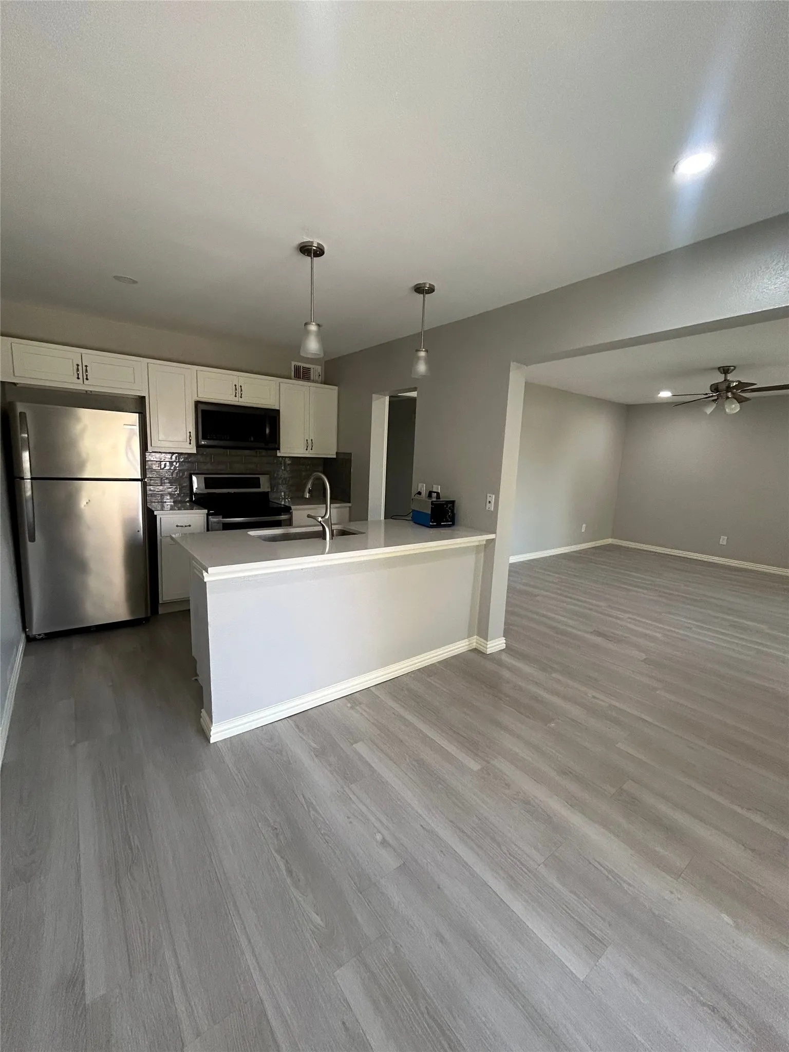 Kitchen featuring stainless steel appliances, pendant lighting, and white cabinetry