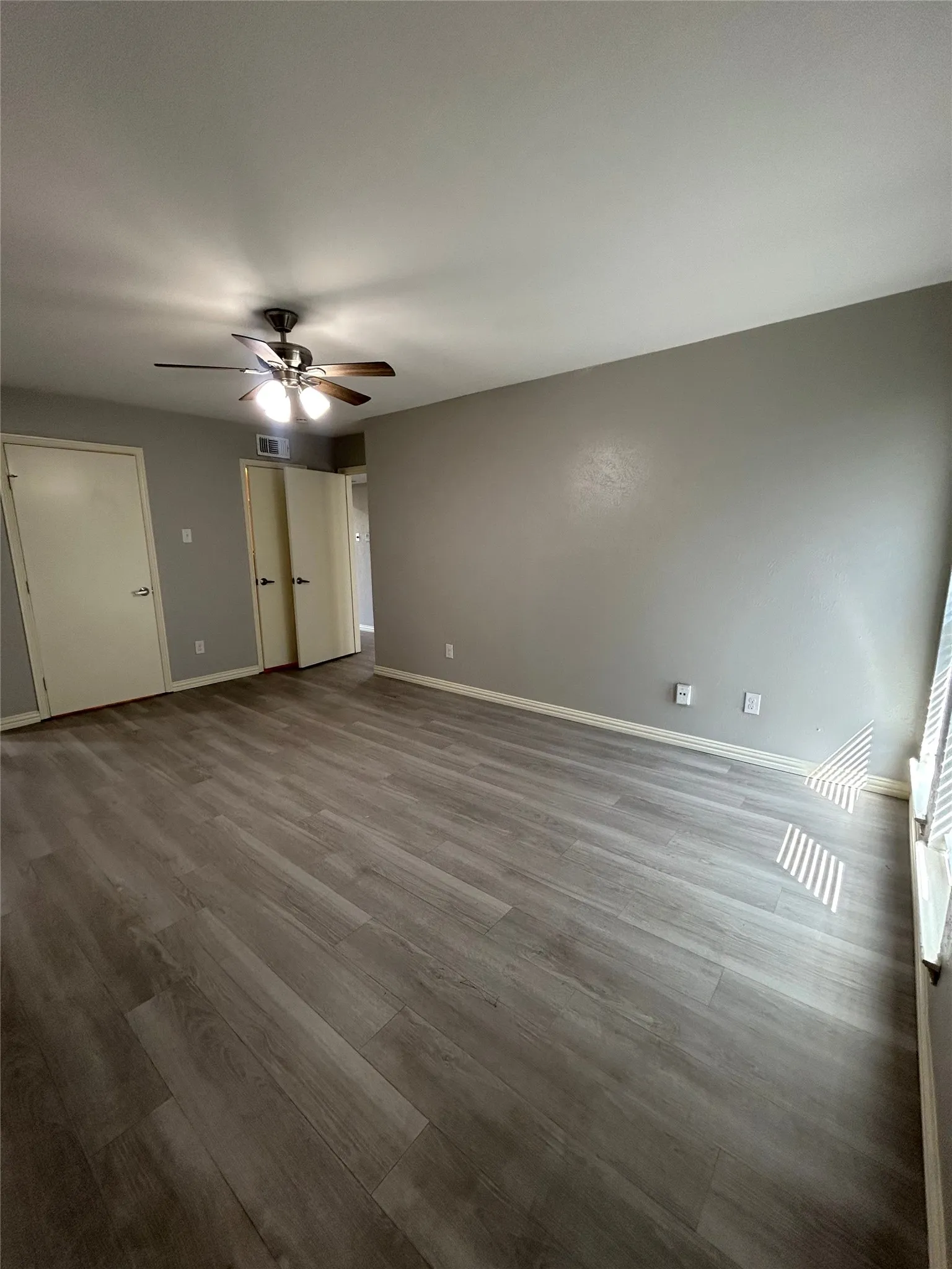 Wood-finish plank flooring throughout, neutral painted walls, and a ceiling fan with integrated lighting