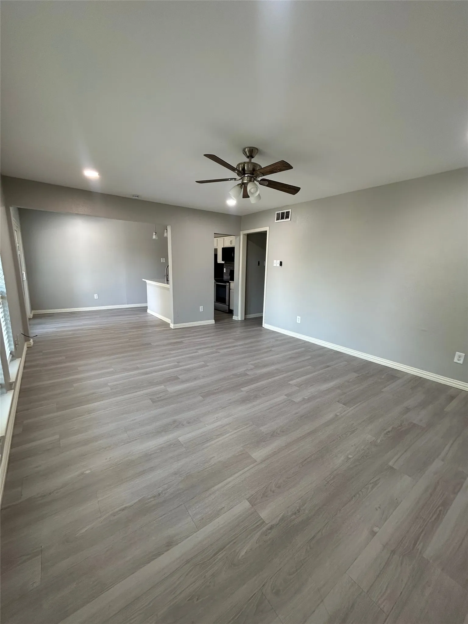 Expansive room featuring wood-finish flooring, neutral paint, recessed lighting, and a ceiling fan